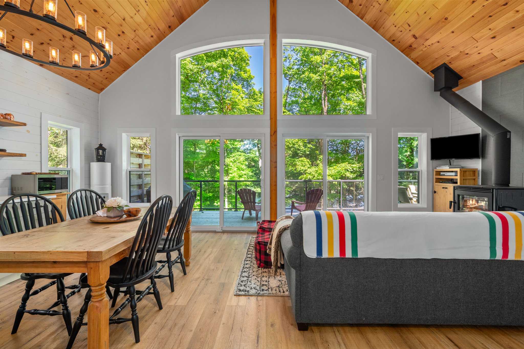 A V-shaped vaulted ceiling with a huge wall of windows. A wood dining table and grey couch face the windows