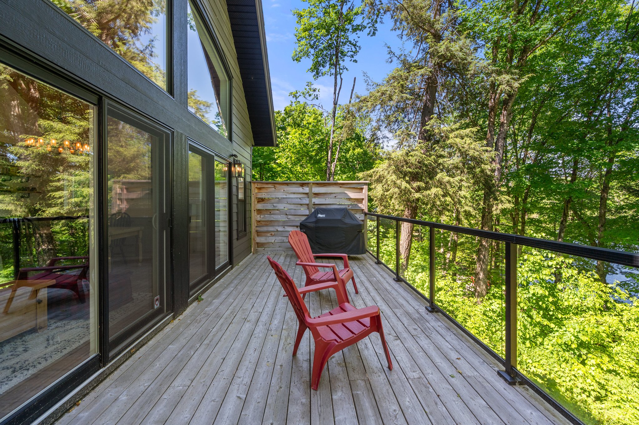 Two red Muskoka chairs outside glass doors