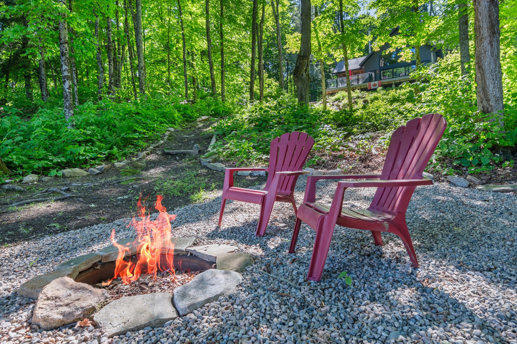 Two red Muskoka chairs sit beside a pit pit