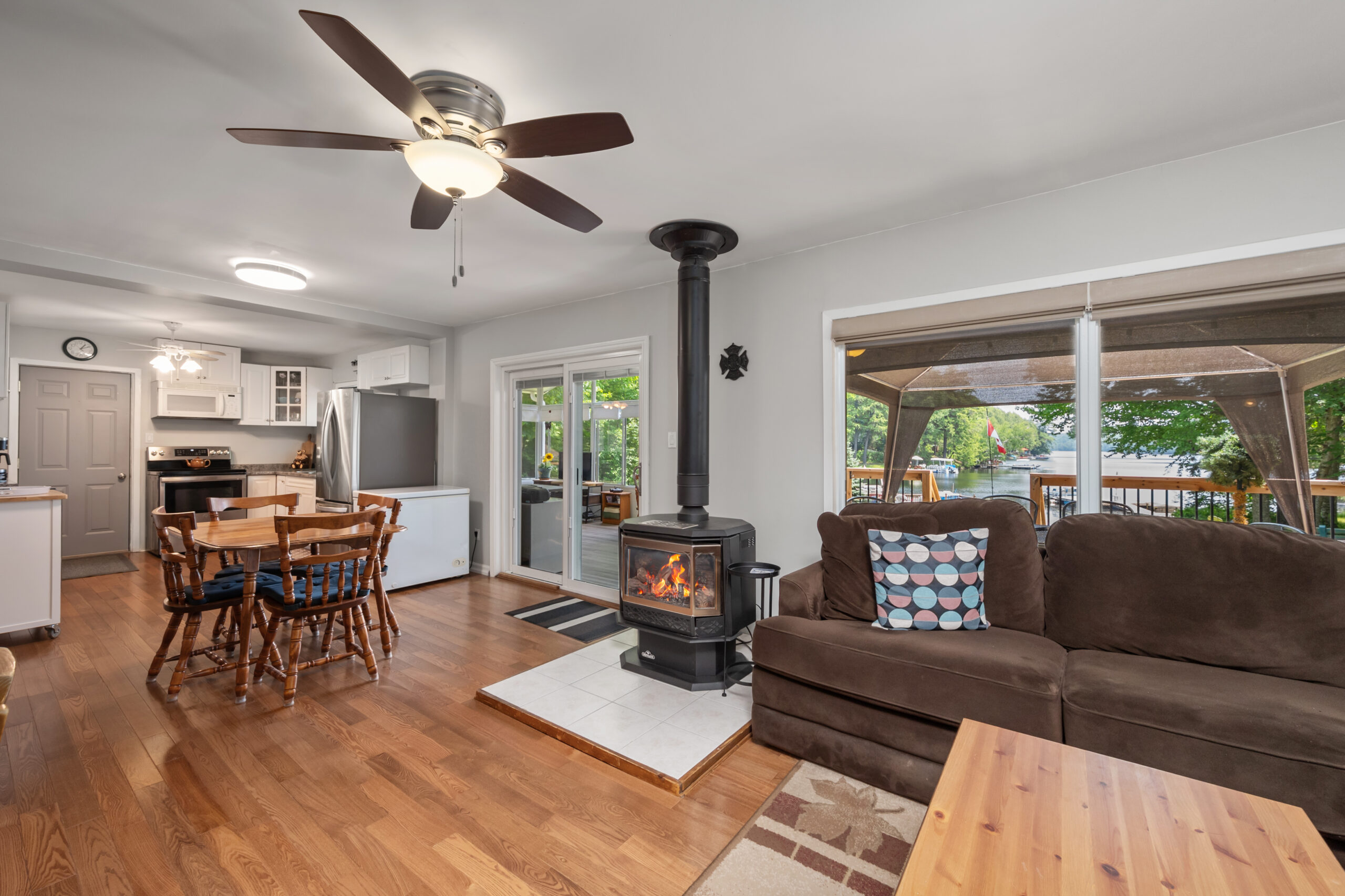 A wood stove next to a brown velvet couch in an open-concept living room with wood floors