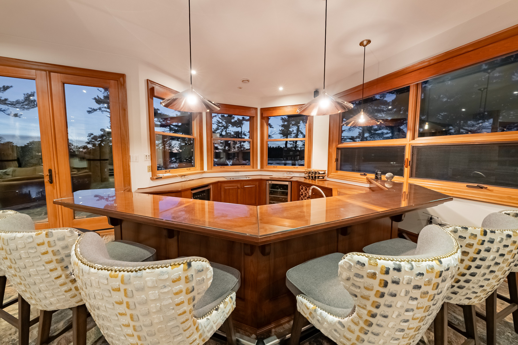 A square-shaped wood bar with white wicker chairs around it