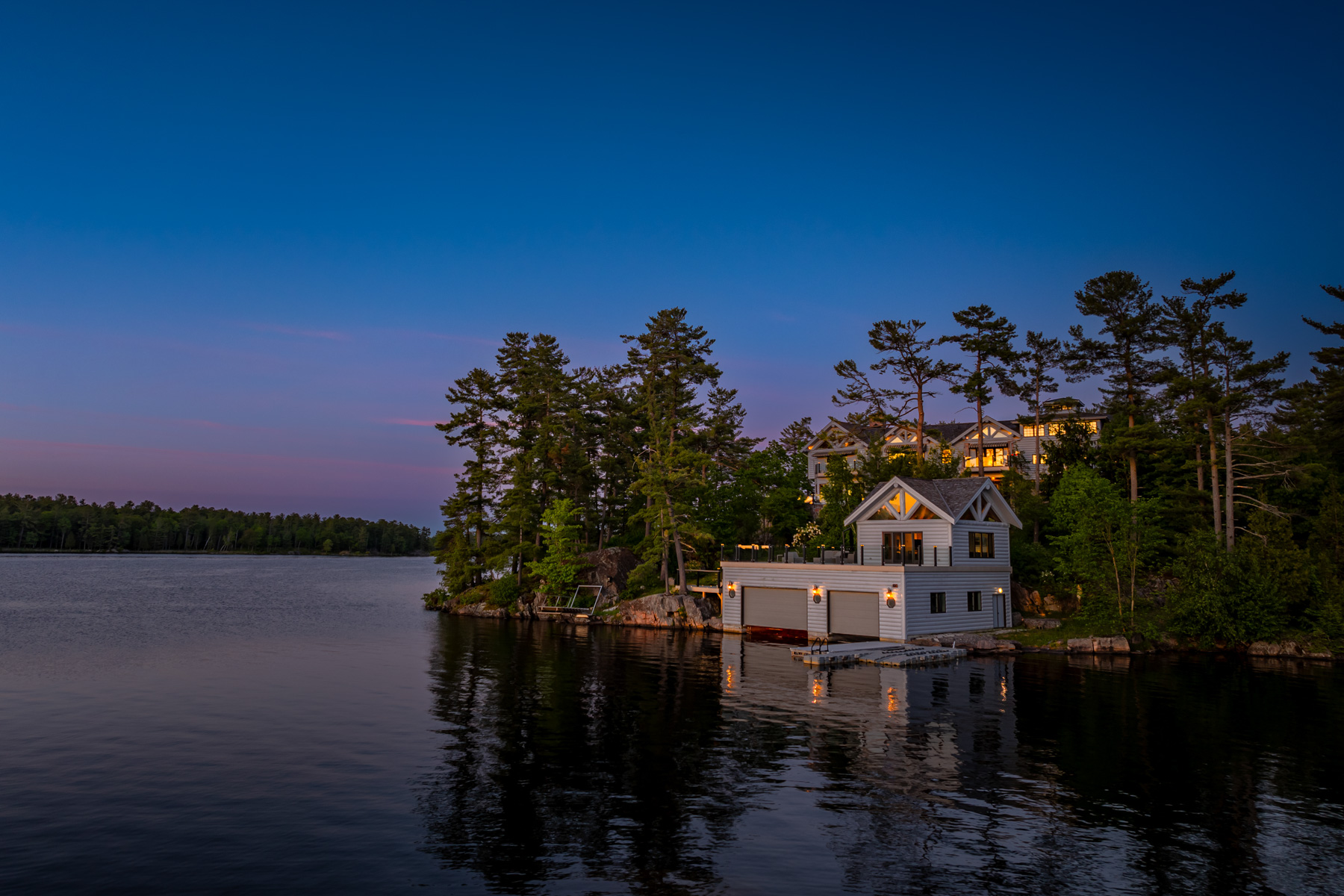 A grey boathouse on the lake at nighttime