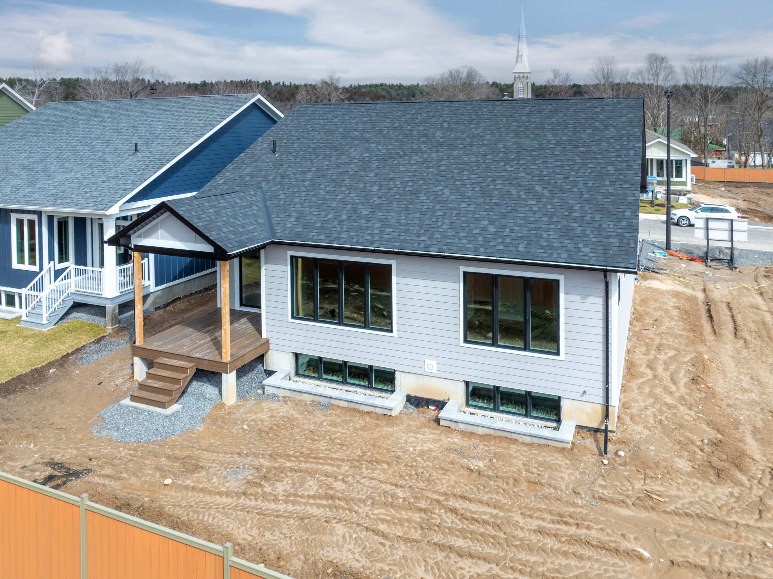 A grey cottage with a covered porch and dirt surrounding