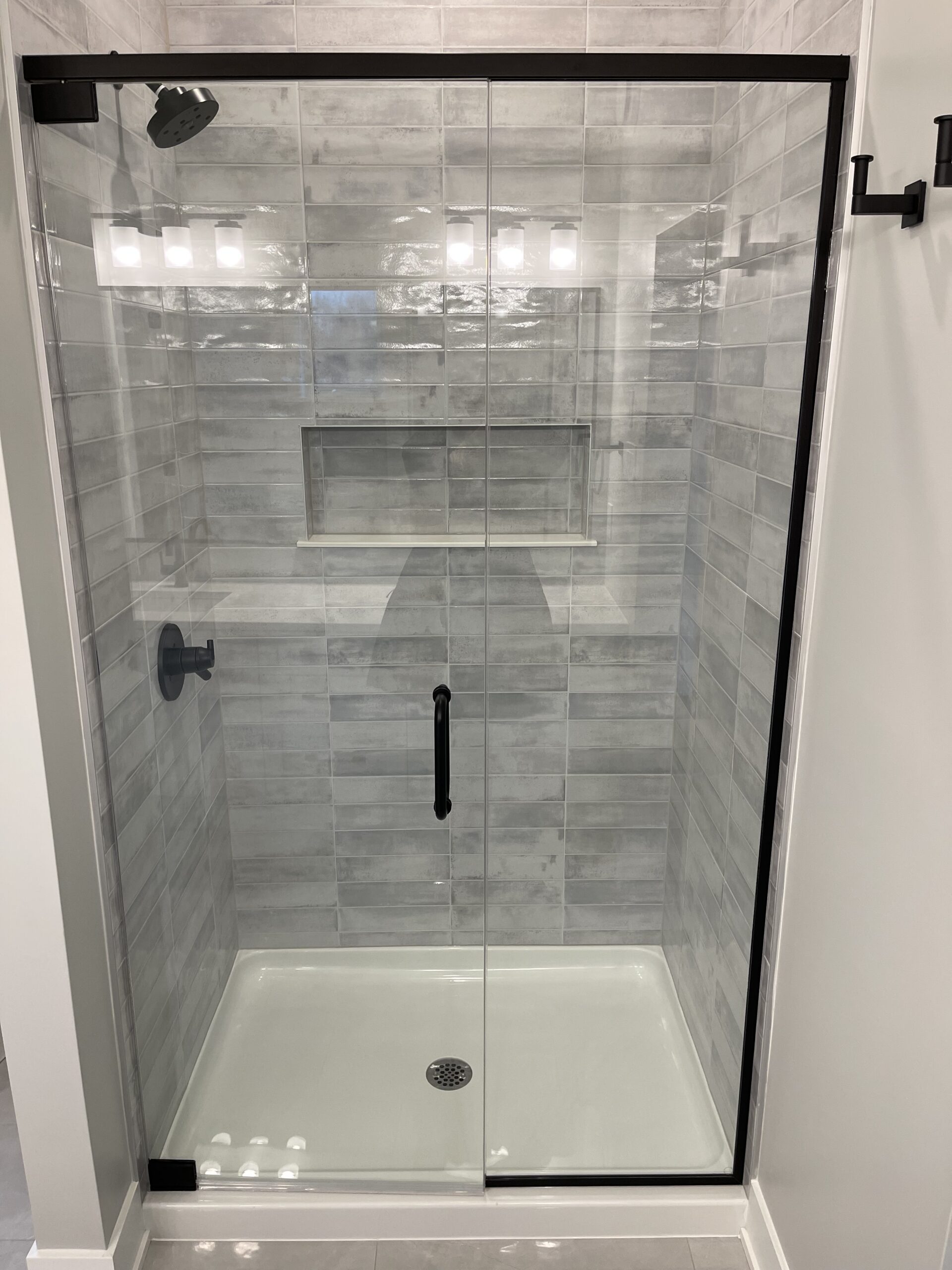 A glass walk-in shower with grey tiles