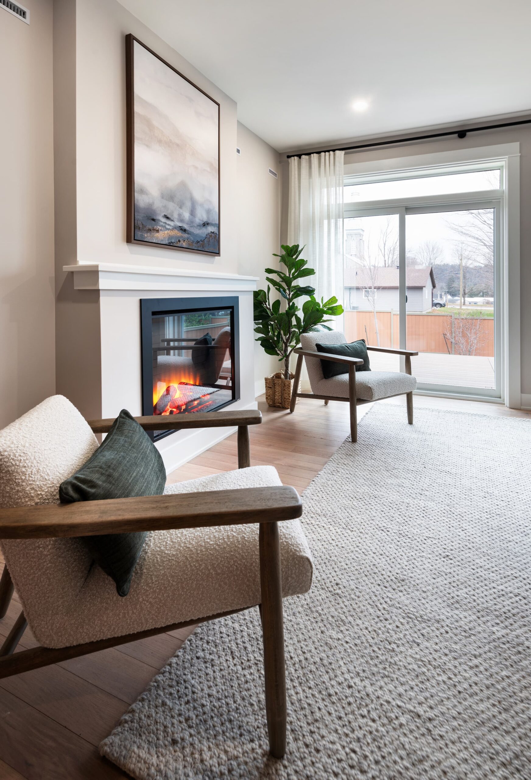 Two white sitting chairs on either side of an electric fireplace