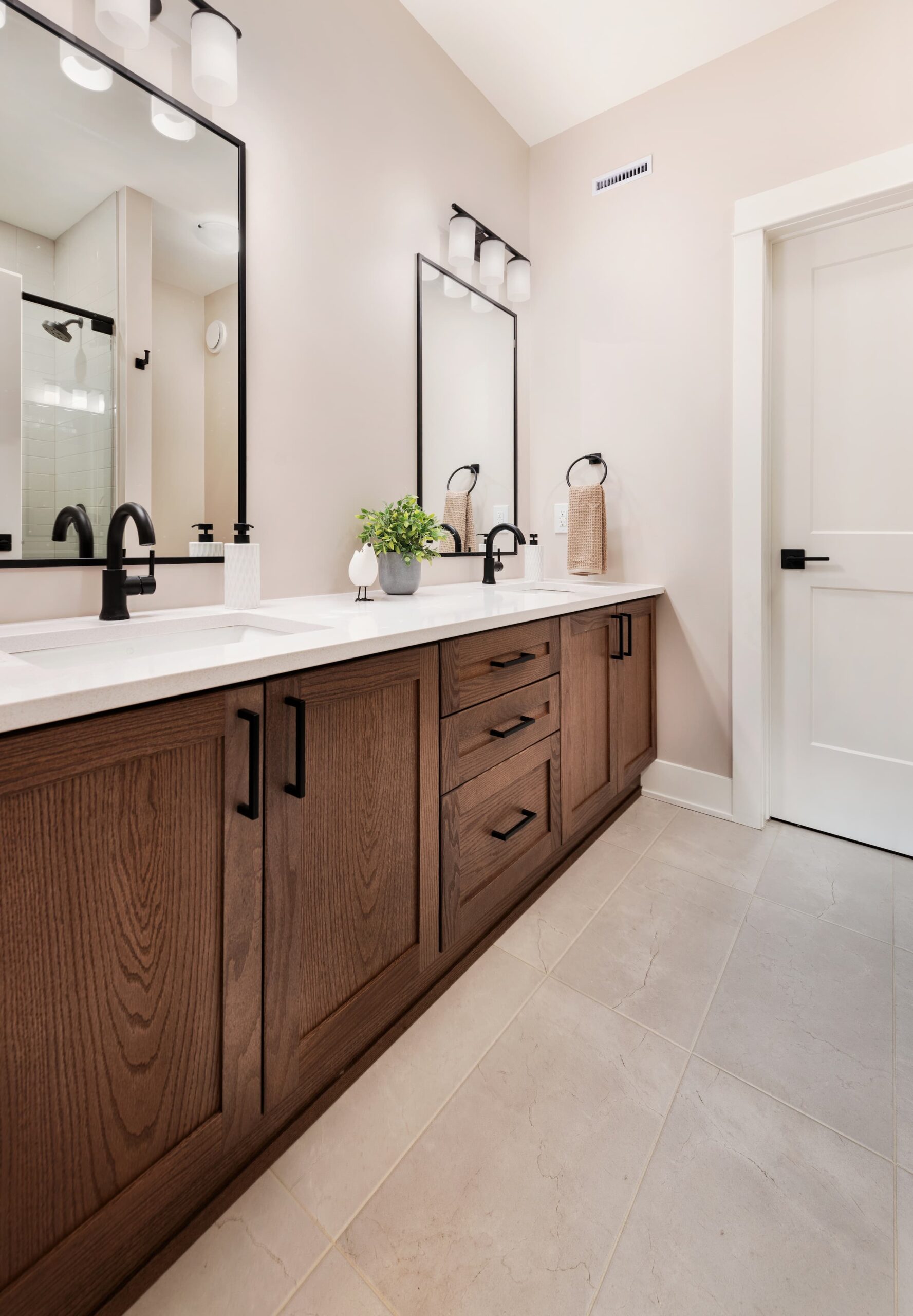 A long brown vanity with white countertops and two sinks