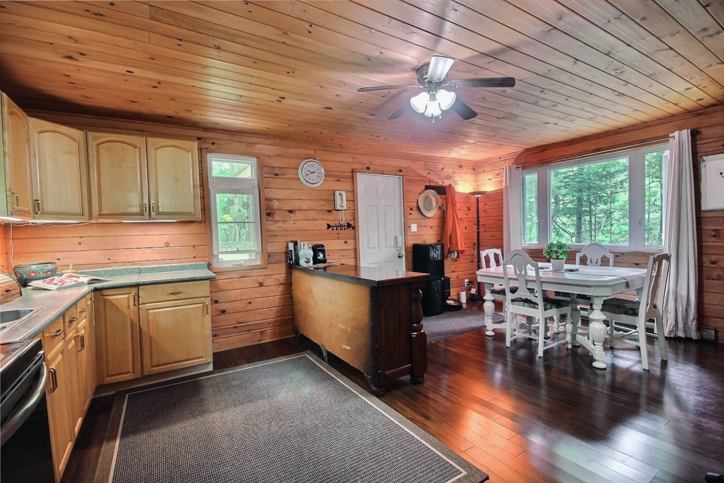 An open-concept kitchen and dining area in a wood-panelled room