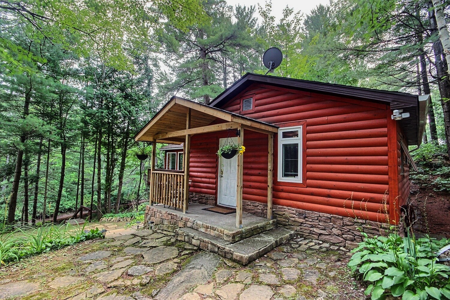 A red panelled cottage with a front porch and white front door