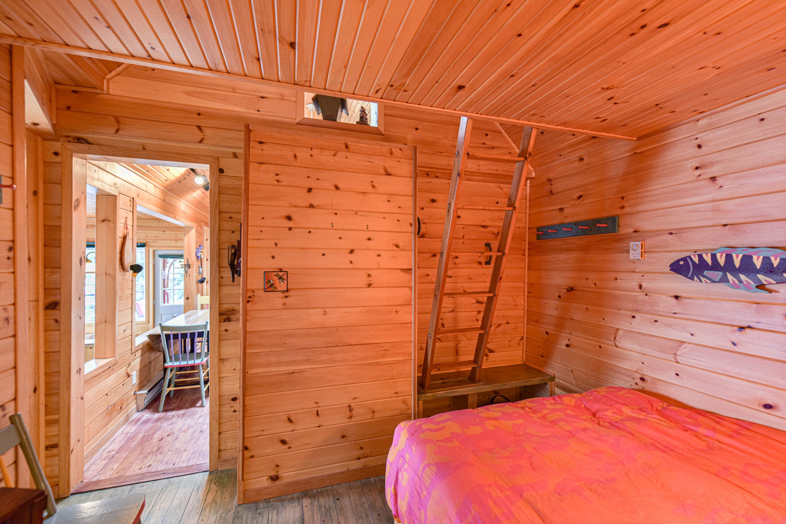 The end of a pink bed faces a wood panelled wall