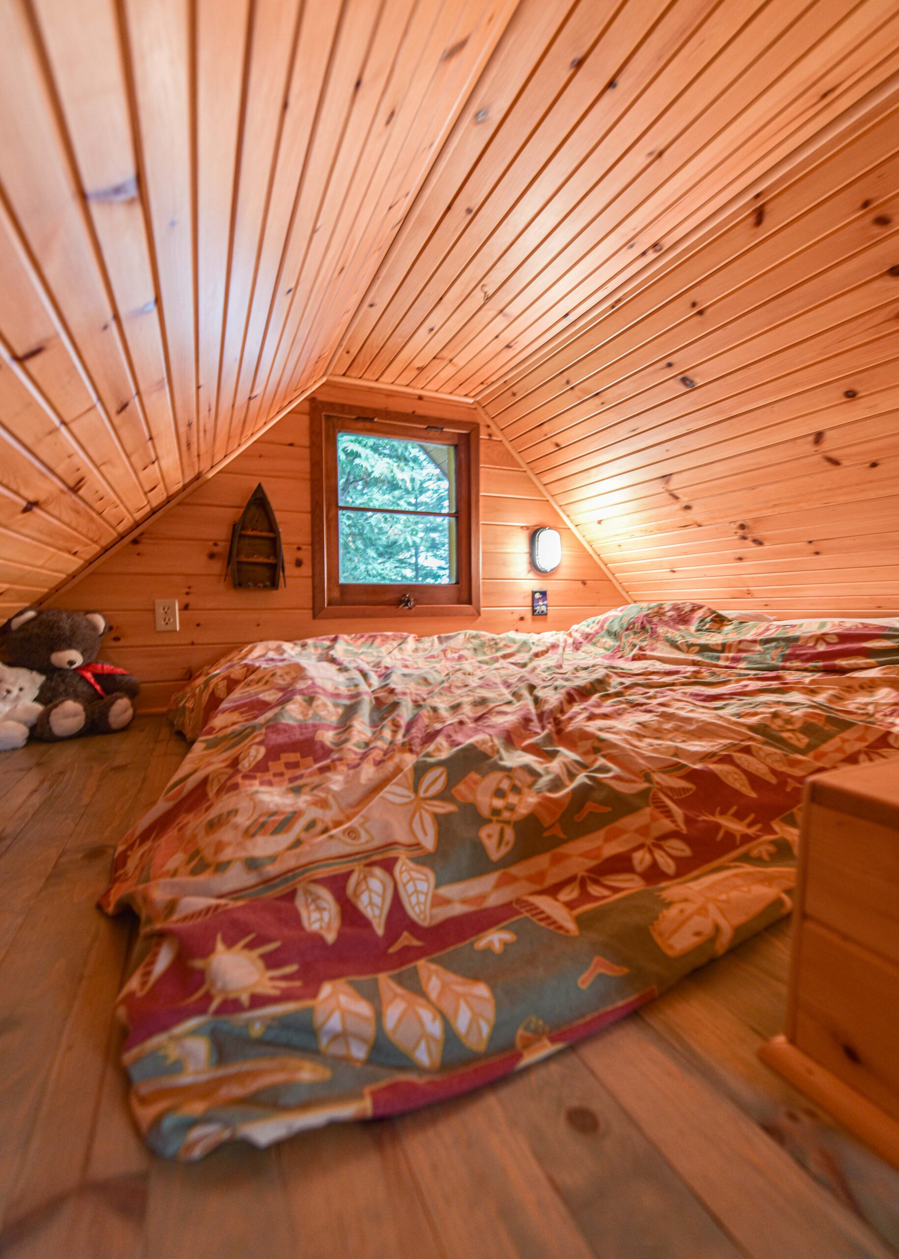 A bed with a patterned cover on the floor of a wooden loft