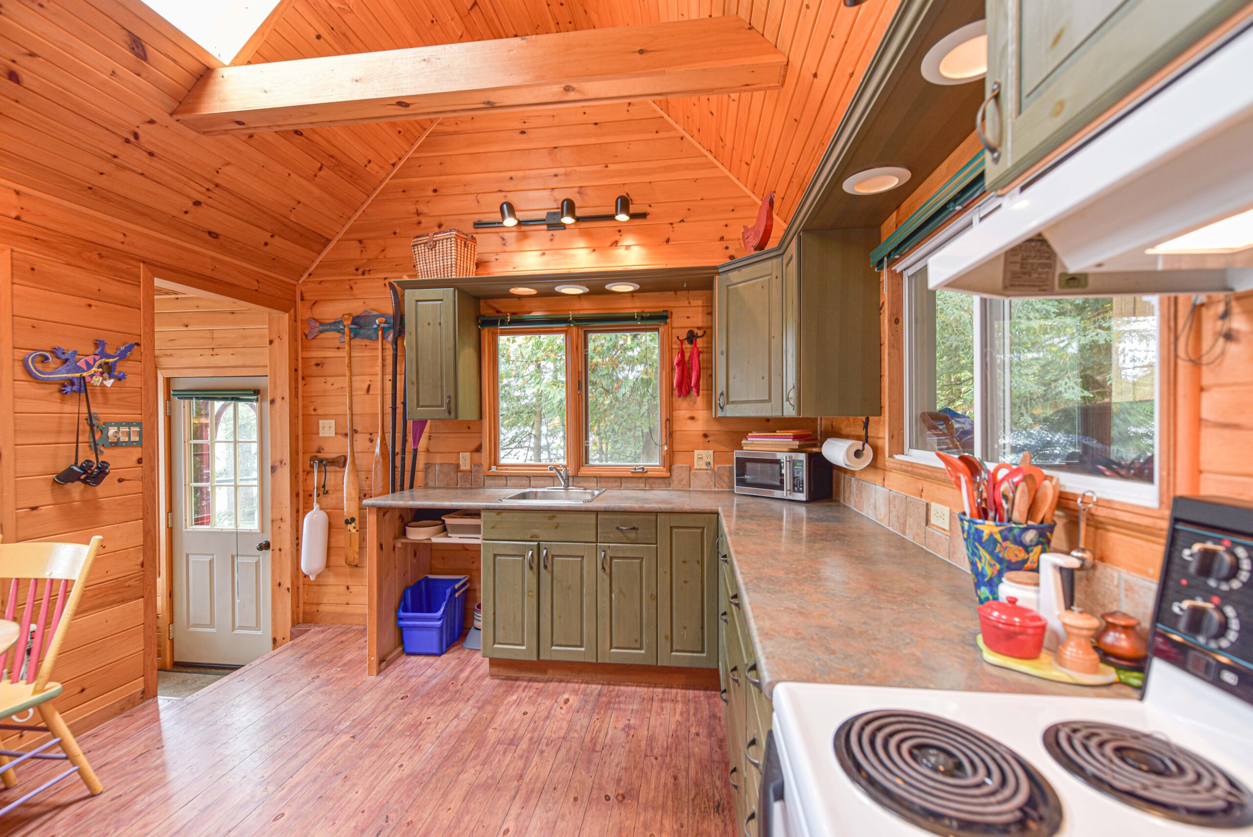 A kitchen with green cabinets in a wood panelled room