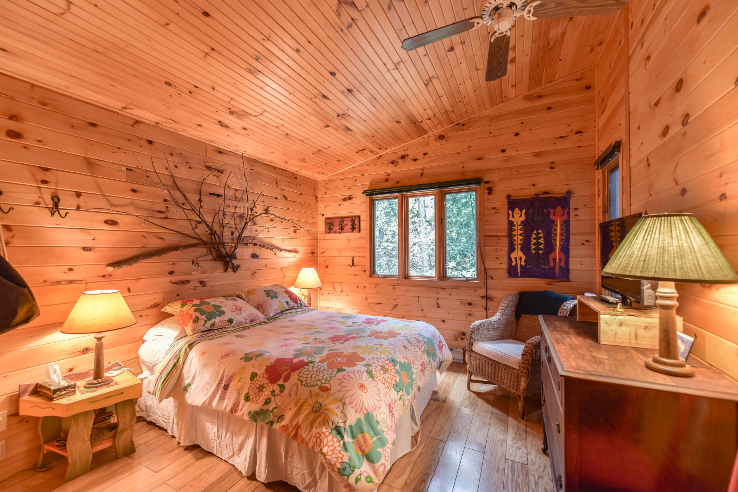A large bed with a a floral cover in a wood panelled room