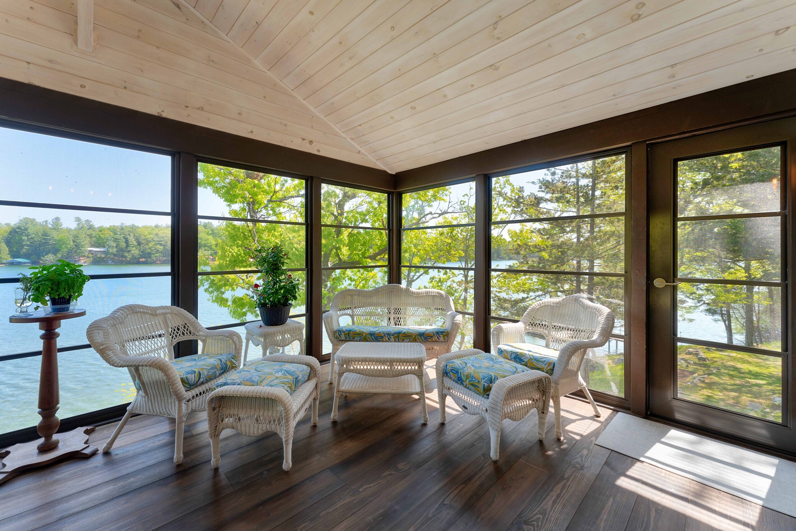 A sitting area with white wicker seats in the corner of a sunroom