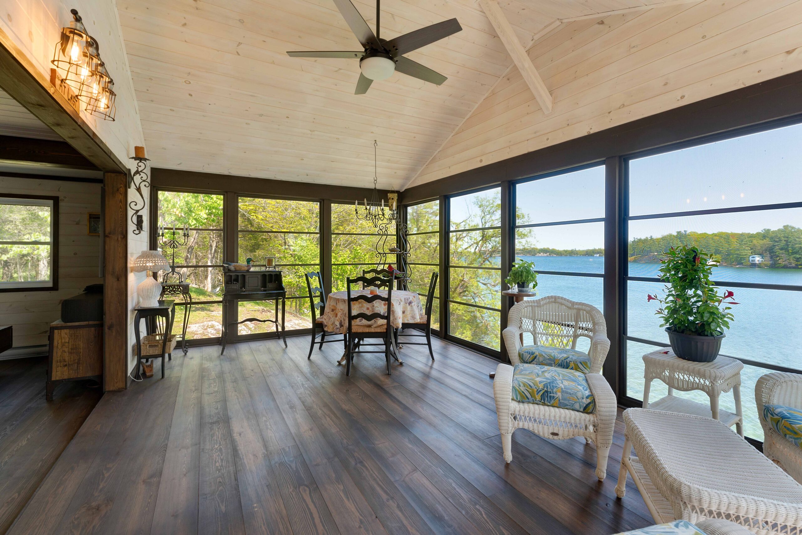 A spacious room with dark wood floors, panoramic views of the water, and a high white ceilings
