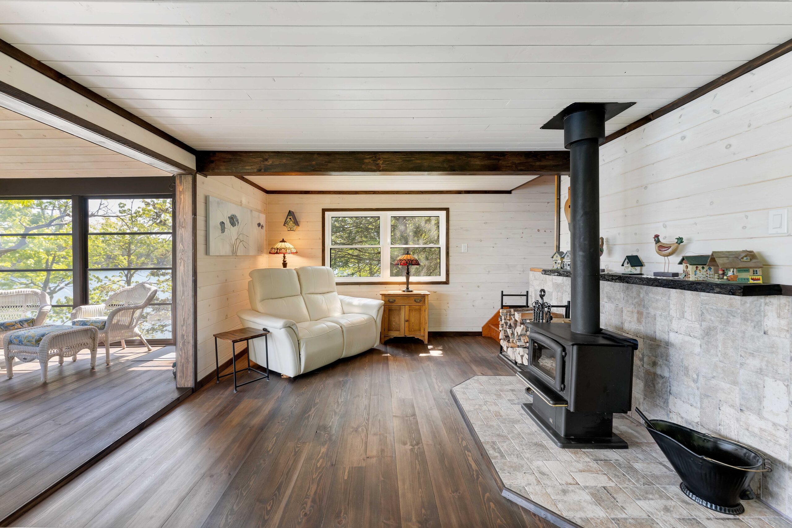 A small white loveseat faces a wood stove