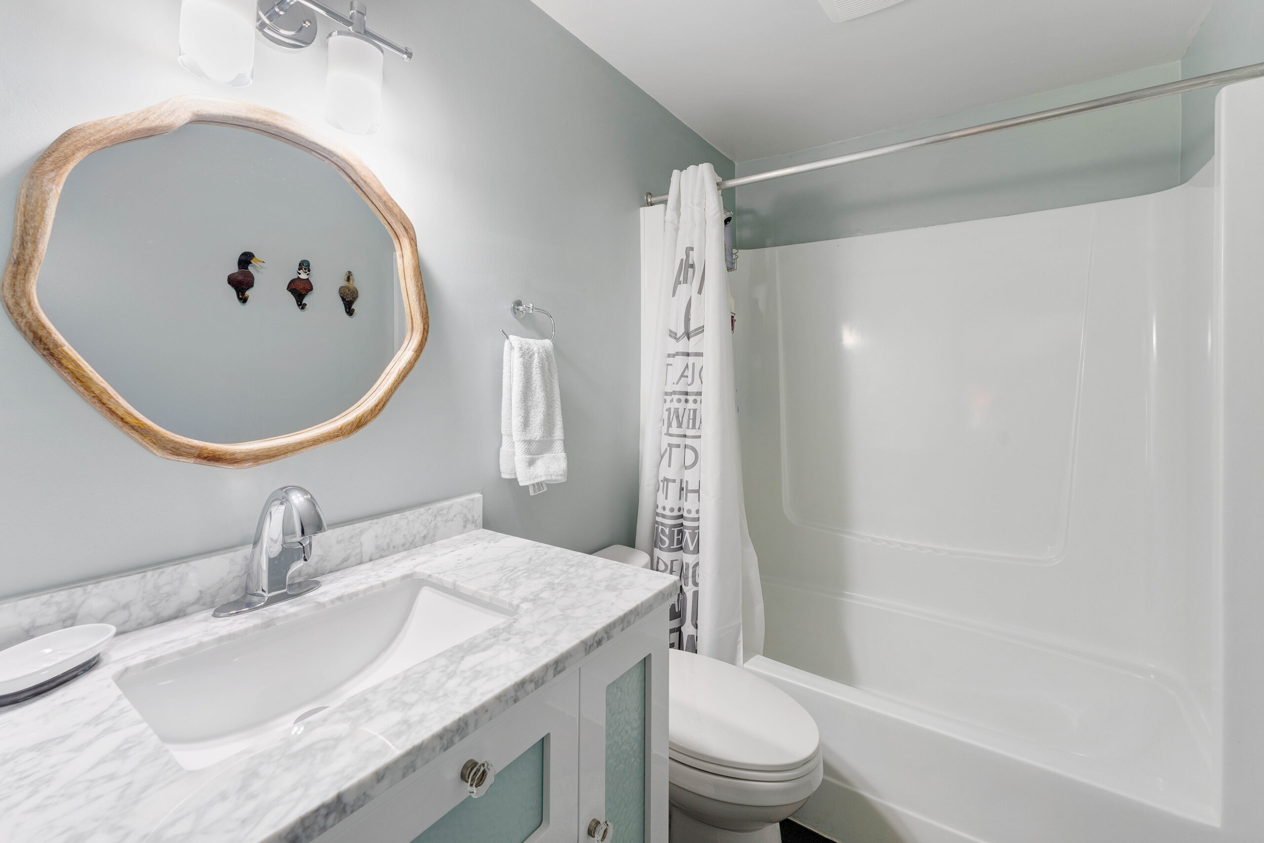 A white vanity next to a toilet and a bathtub/shower