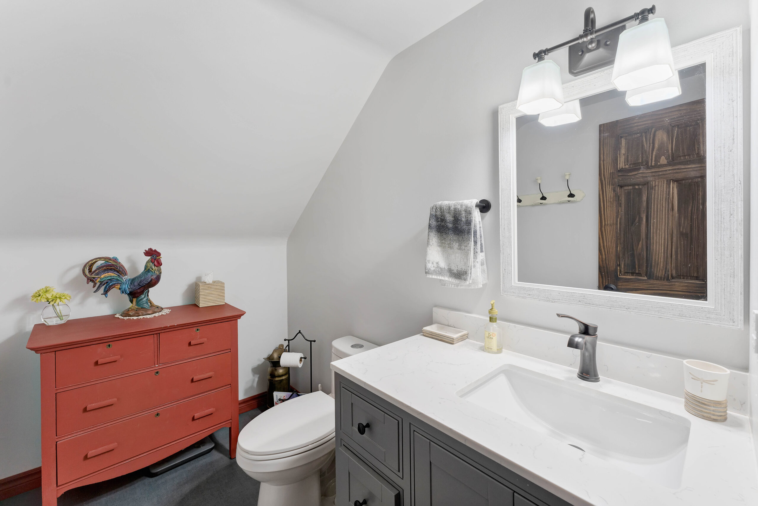 A small bathroom with a toilet and grey vanity
