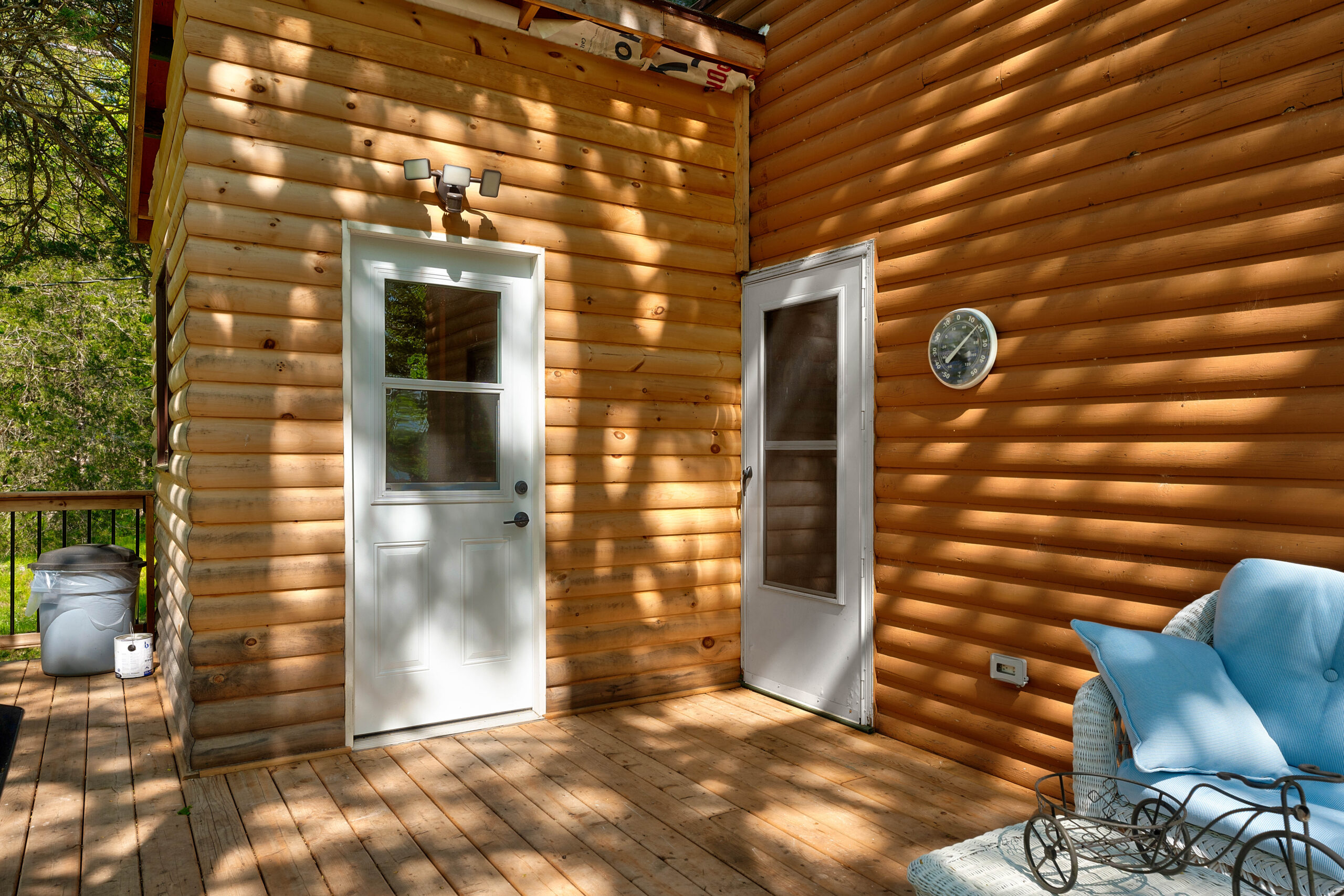 Two white doors are perpendicular on a wood-paneled building