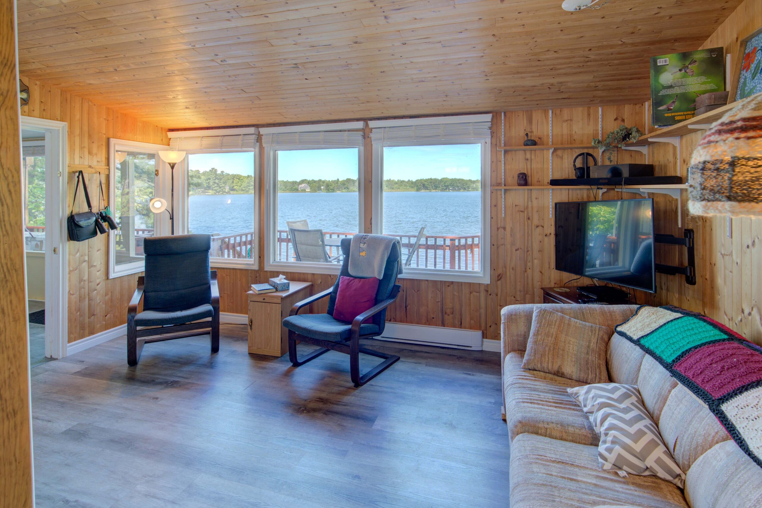 To the right, a large cream-coloured couch. Two black chairs face away from a large window