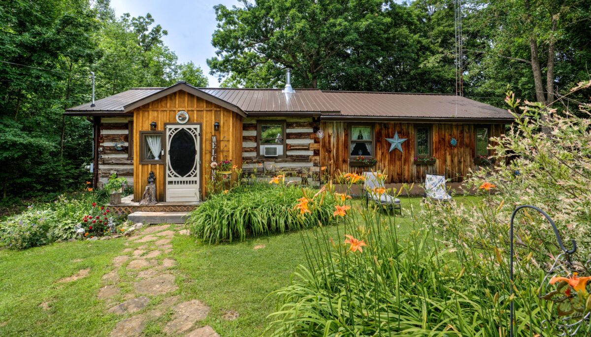 A bungalow log cabin with a large green yard