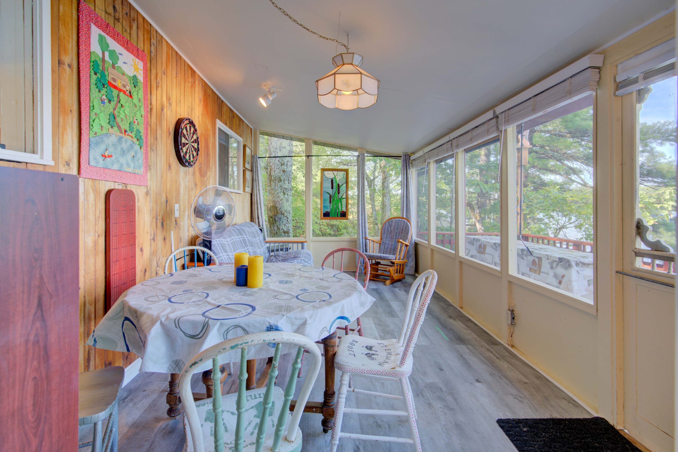 A round table with a floral tablecloth in a window-filled room