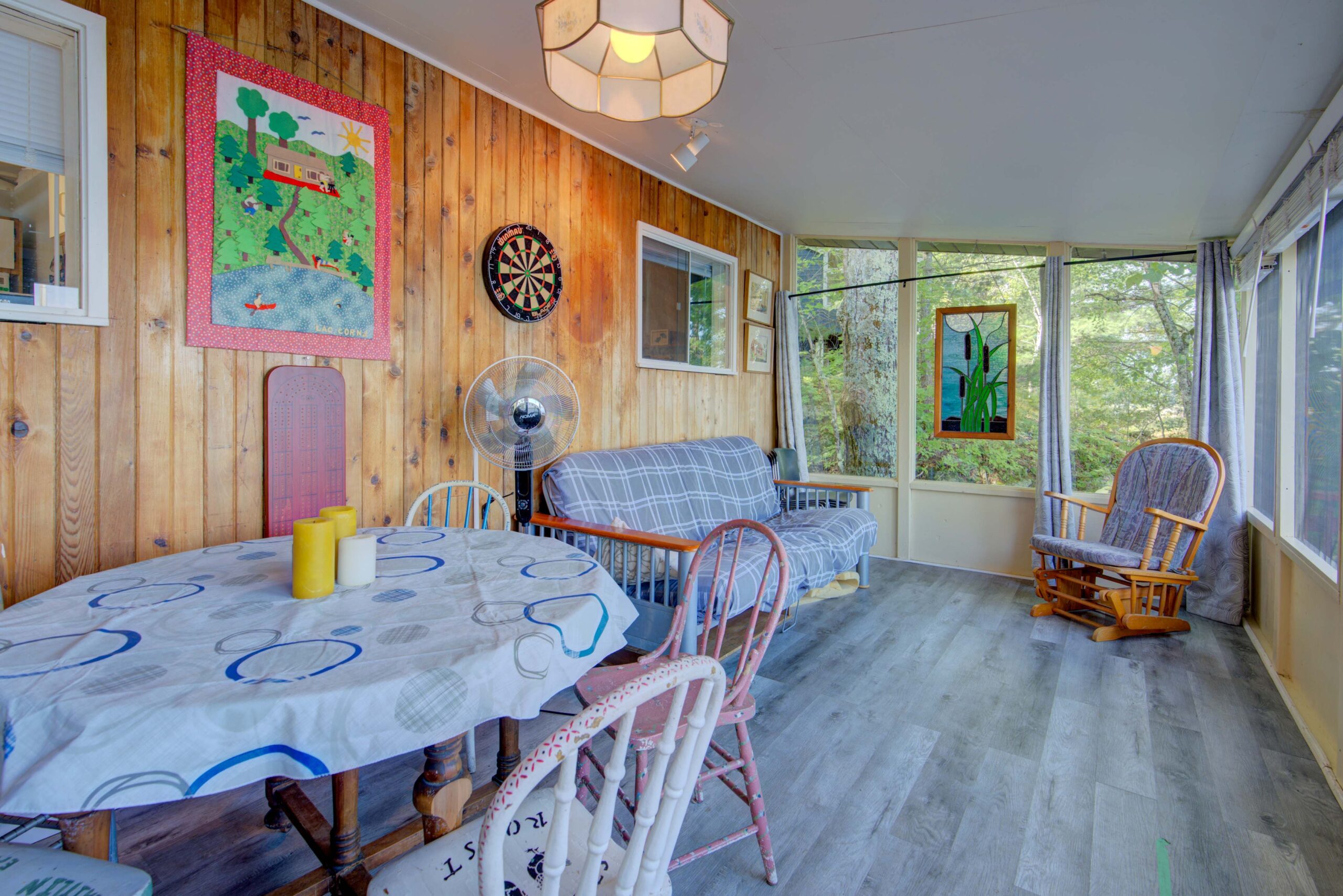 A round table with a floral tablecloth in a window-filled room