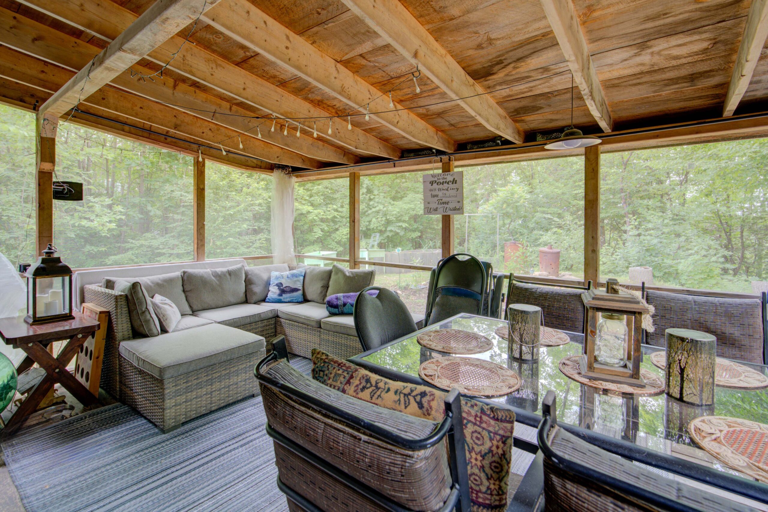 A beige couch and small dining area in a screened-in porch