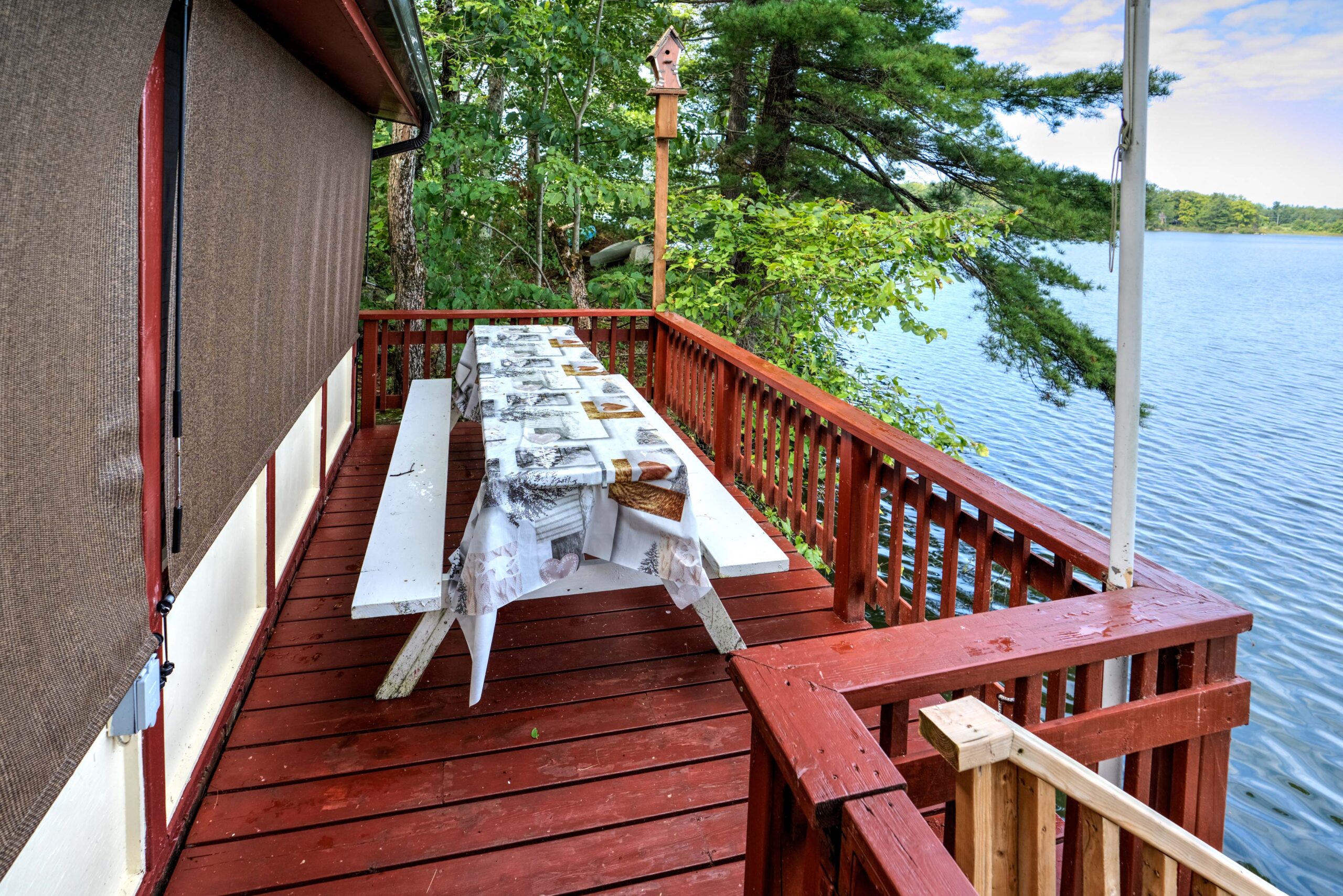 A picnic table with a floral tablecloth on a red deck