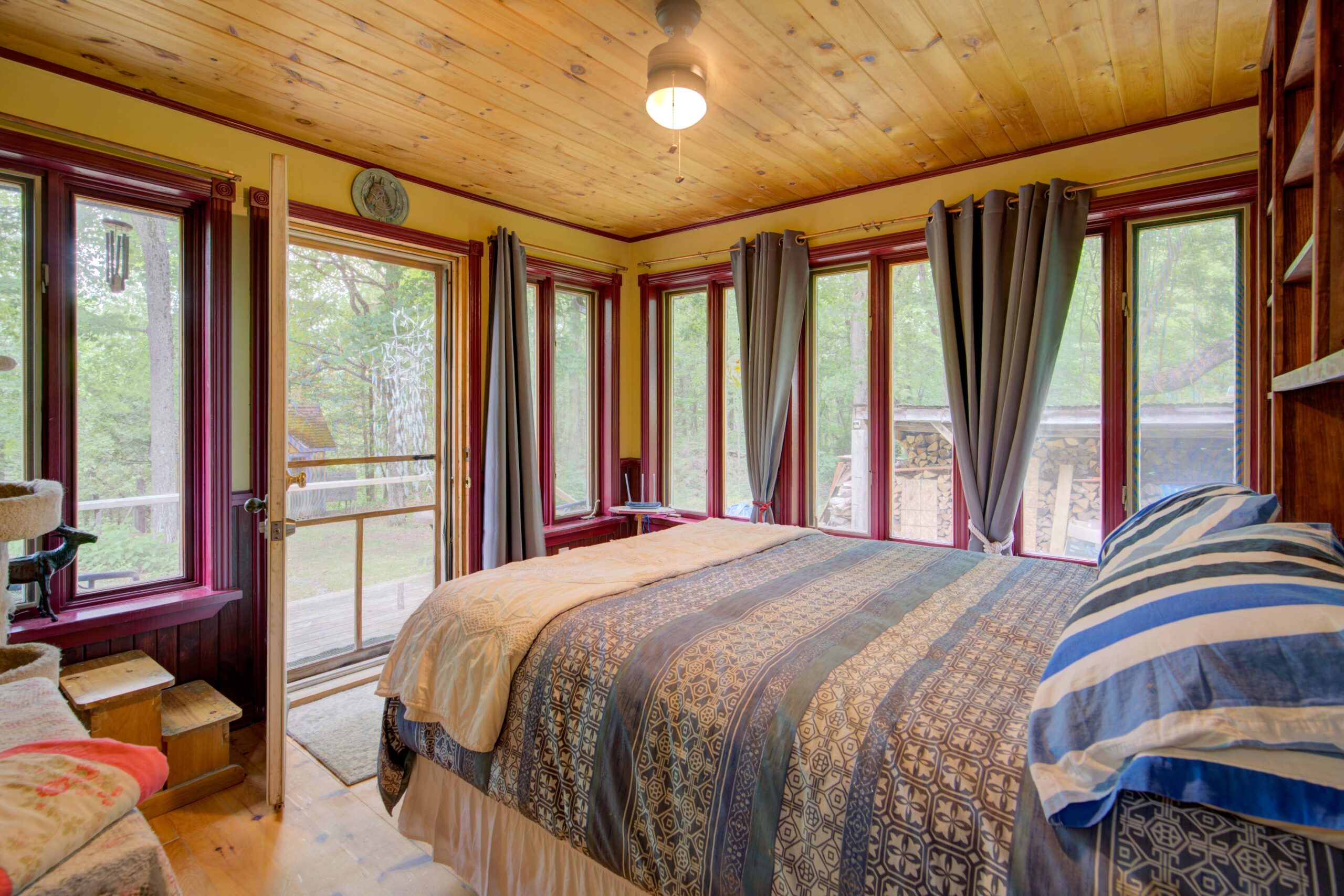 A blue bed faces a screened-in porch with wood ceilings
