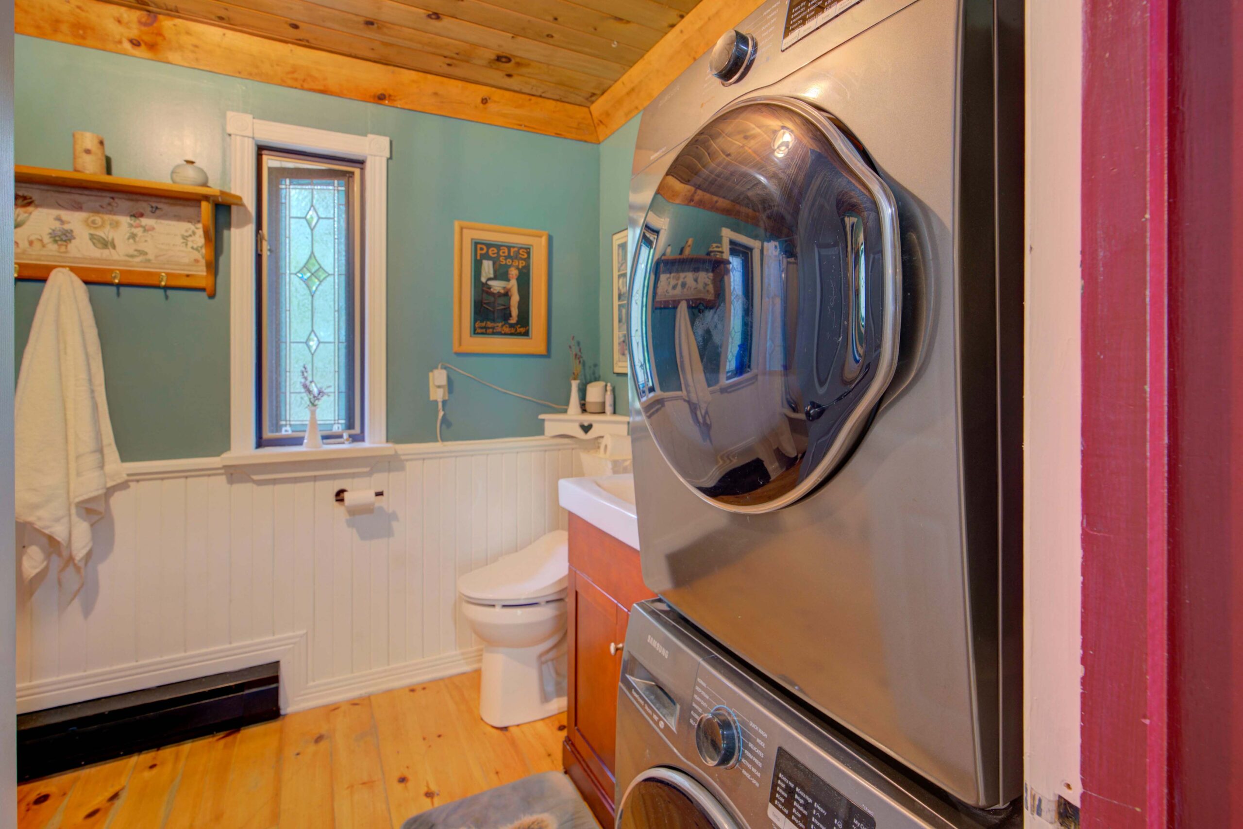 Stacked laundry machines in a teal bathroom