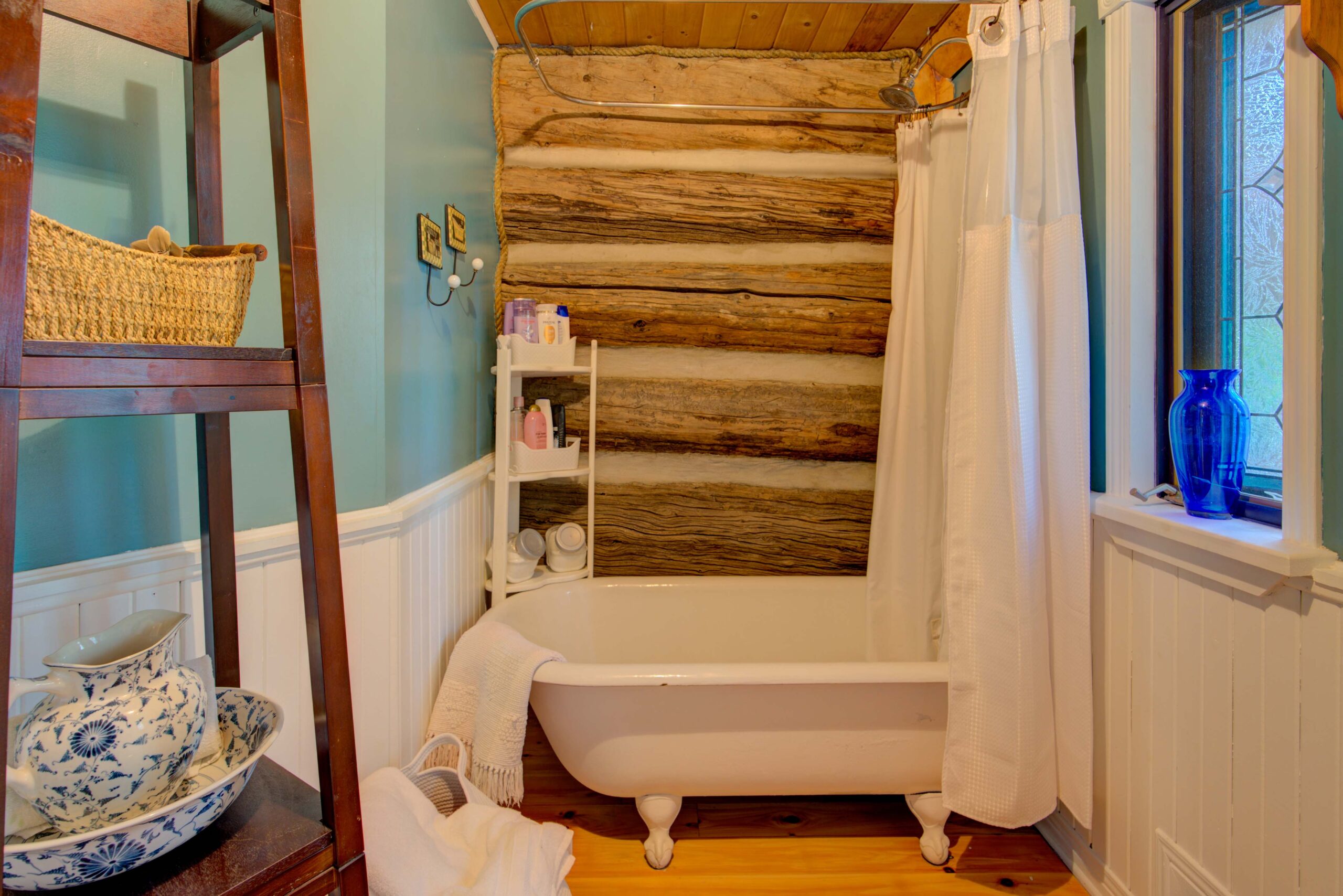 A clawfoot white bathtub with a wood-paneled wall behind it