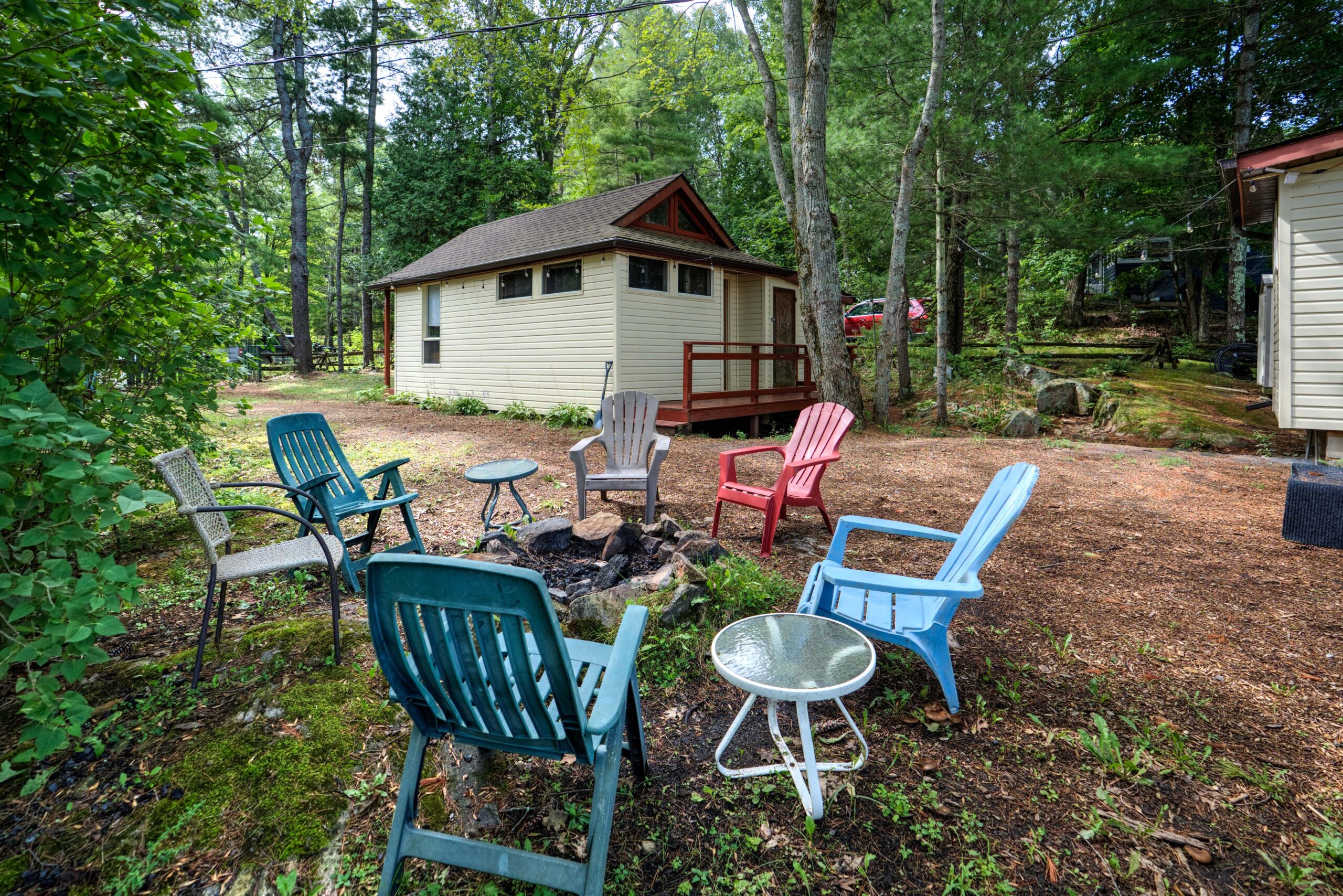 A small fire pit with blue and red Muskoka chairs around