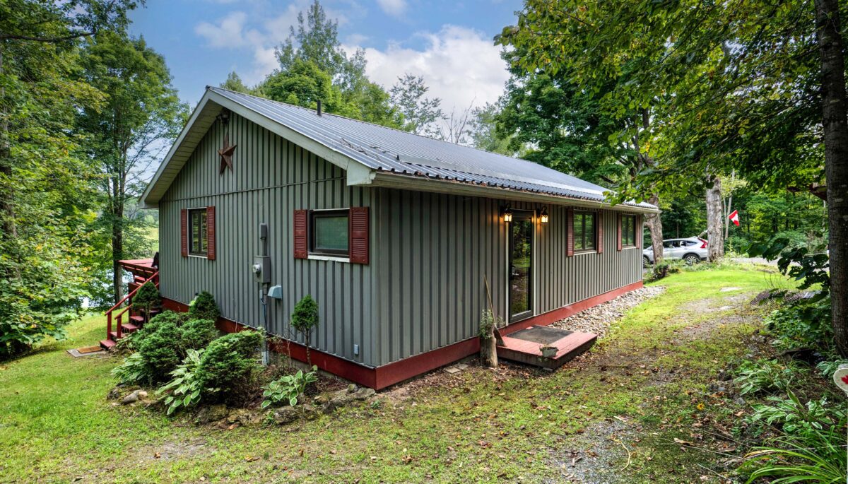 A grey panelled cottage with red trim