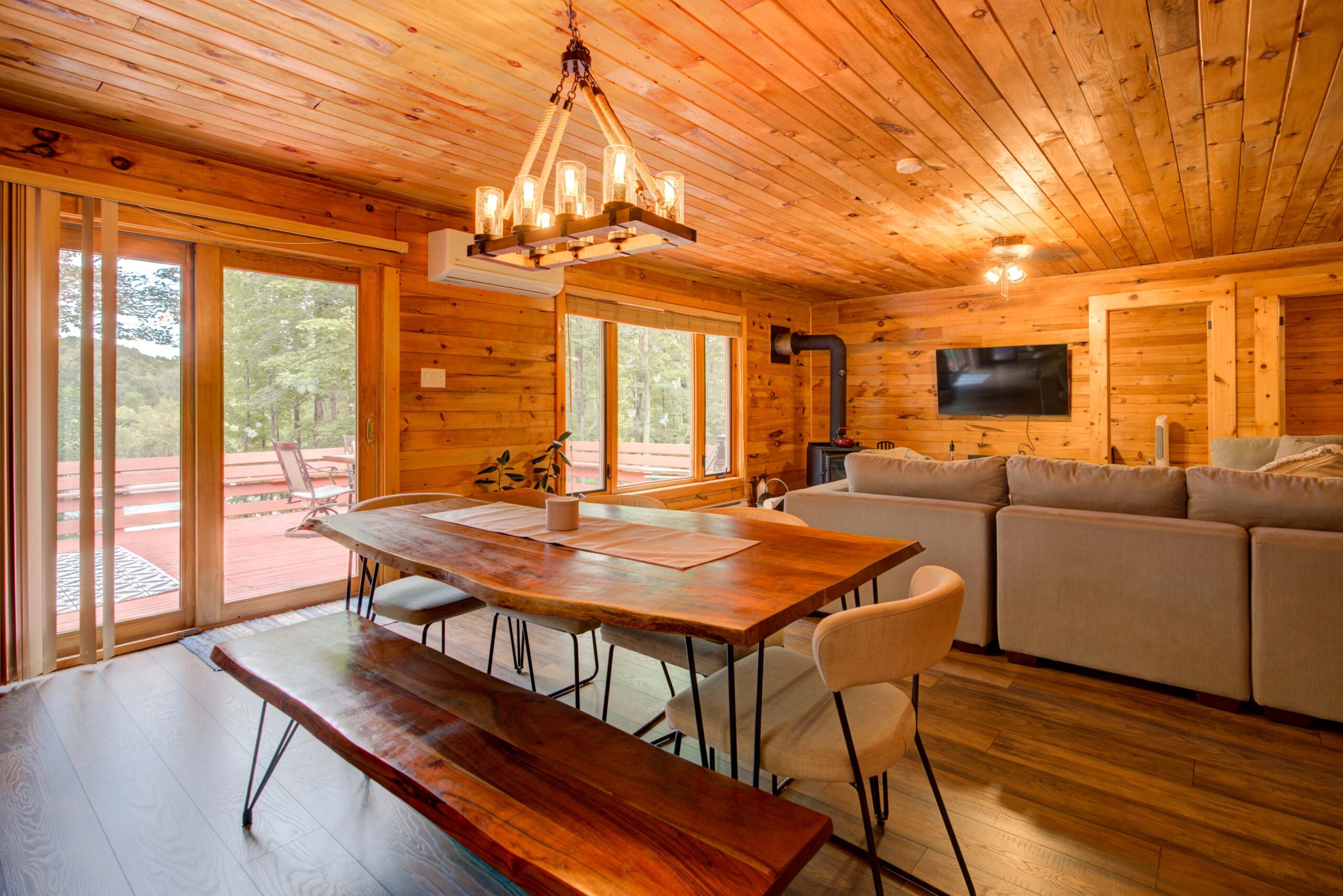 A large wood table in a spacious room faces a bright window and the back of a cream couch