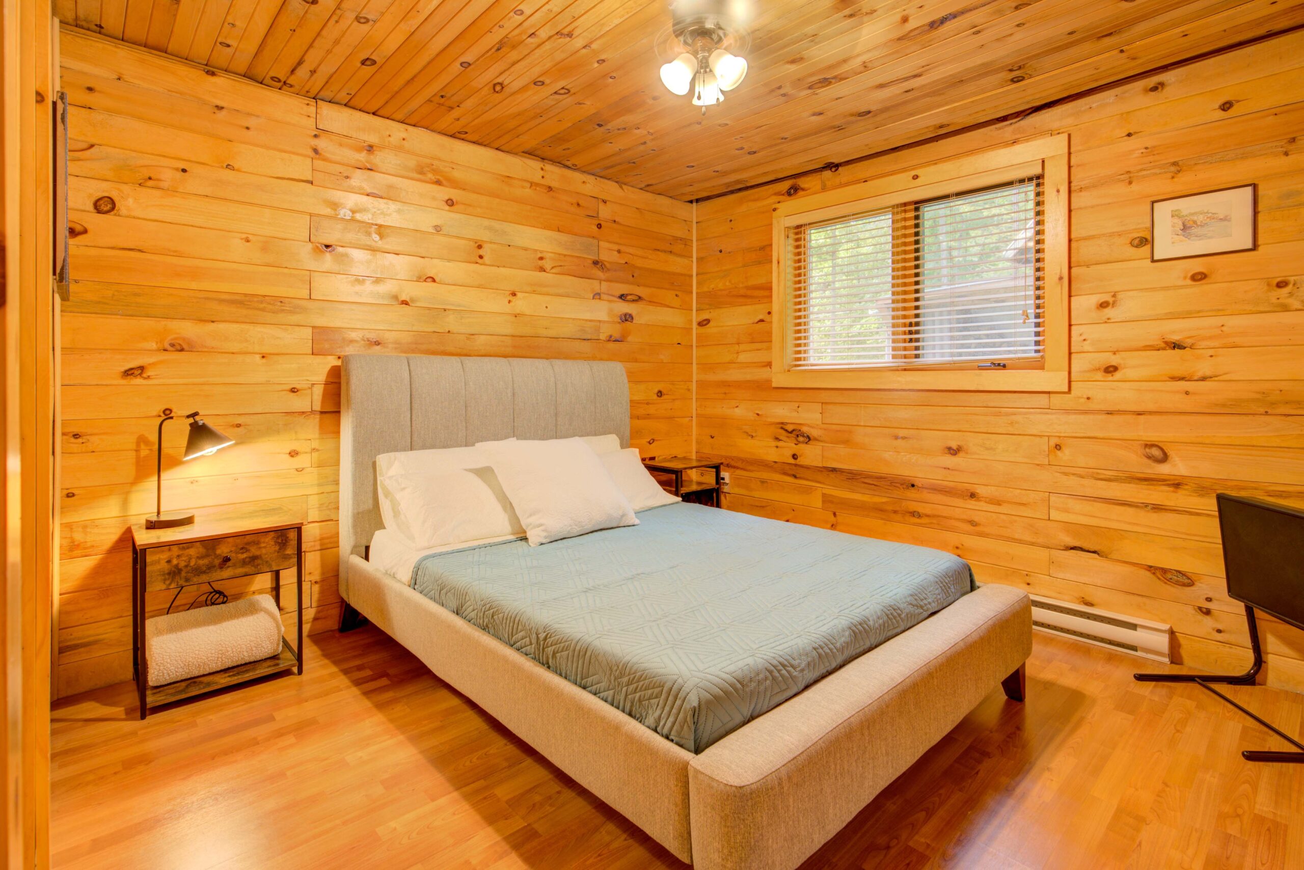 A white bed with a blue bedspread in a wood-panelled room