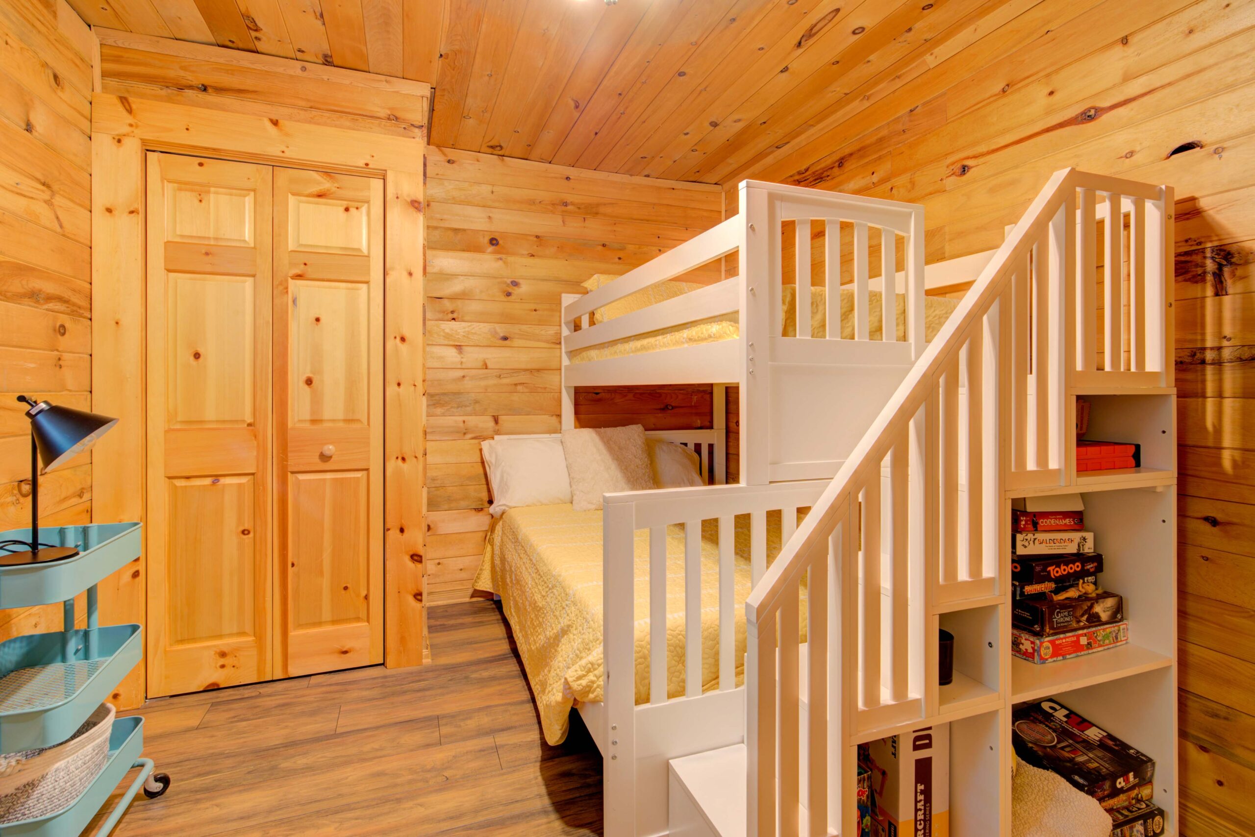 White bunk beds with yellow covers and white steps in wood-panelled room