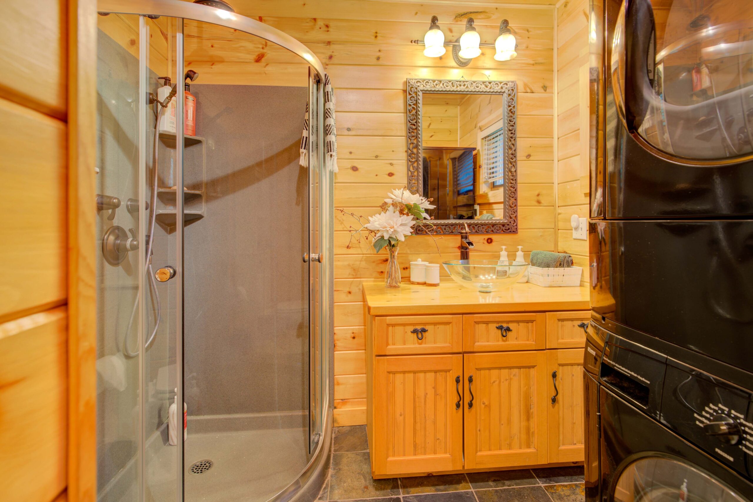 A walk-in glass shower in a wood-panelled bathroom witha wood cabinet