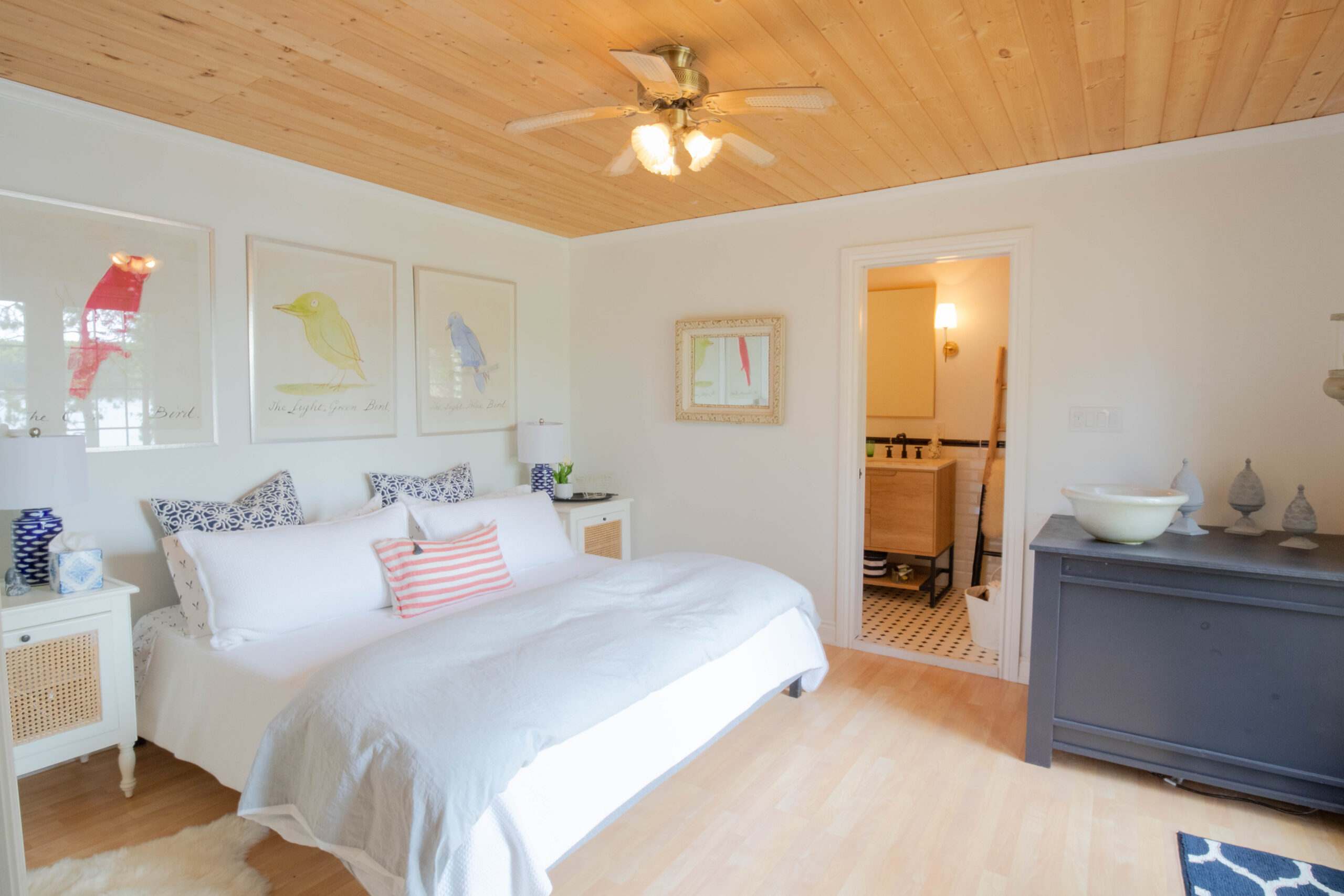 A large white bed on a beige carpet with three pictures hanging above