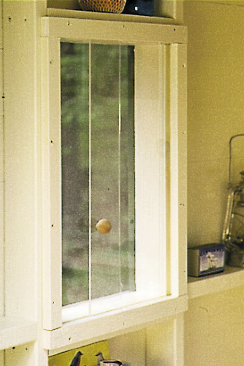 A closeup of an outhouse window with a sliding plexiglas partition