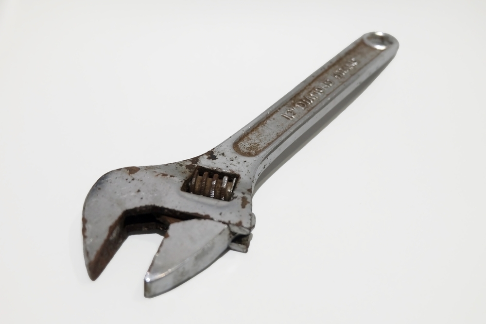 A rusty adjustable wrench against a white background
