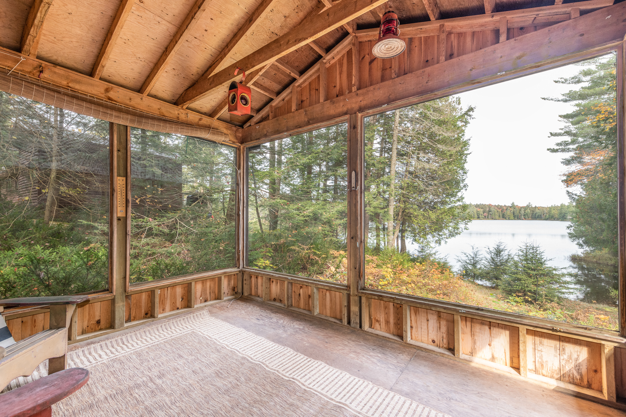 A spacious wood sunroom. Outside the windows, spacious trees and a lake