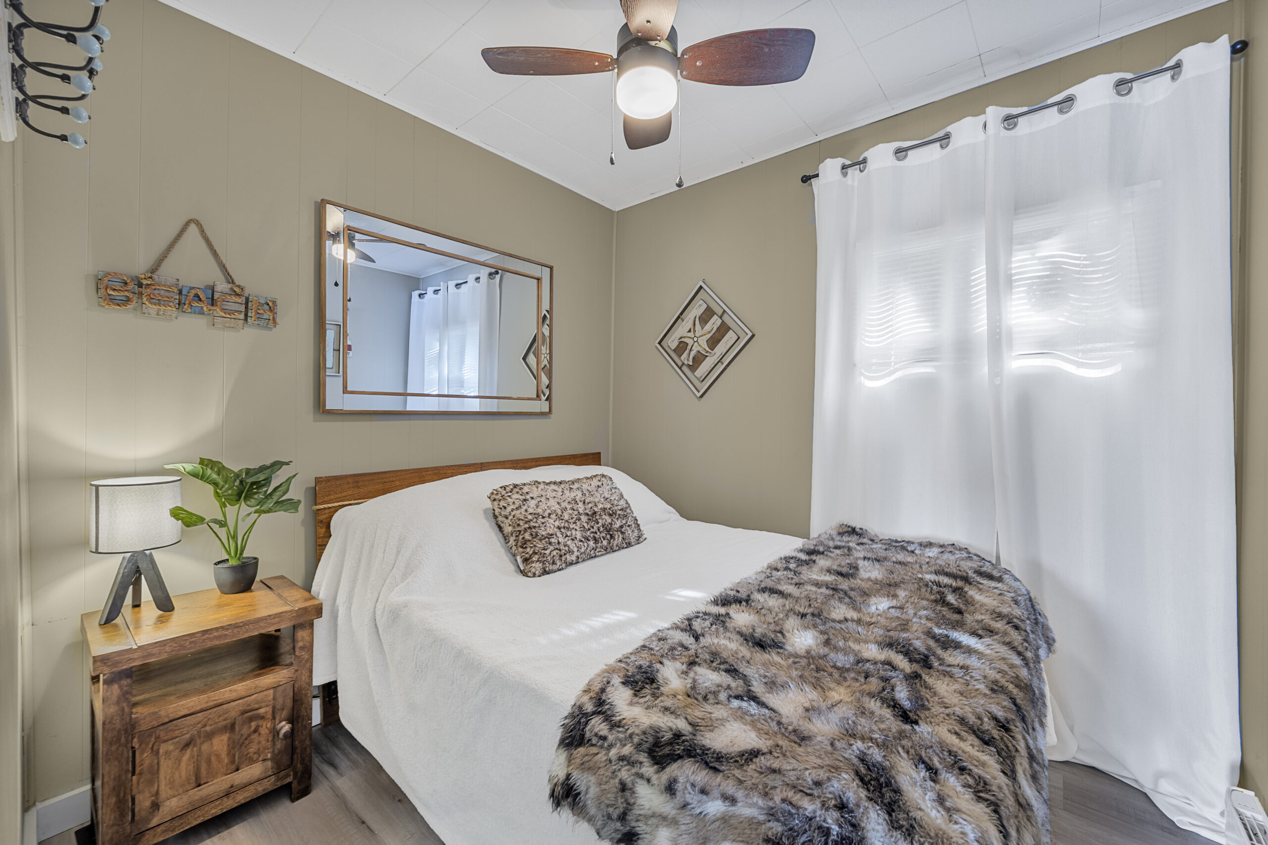 A small white bed with a fuzzy throw blanket