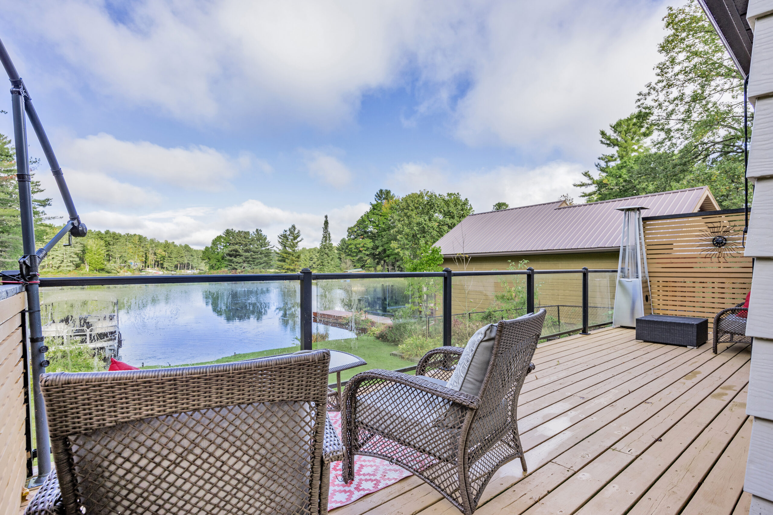 Two wicker chairs on a brown deck face a lake