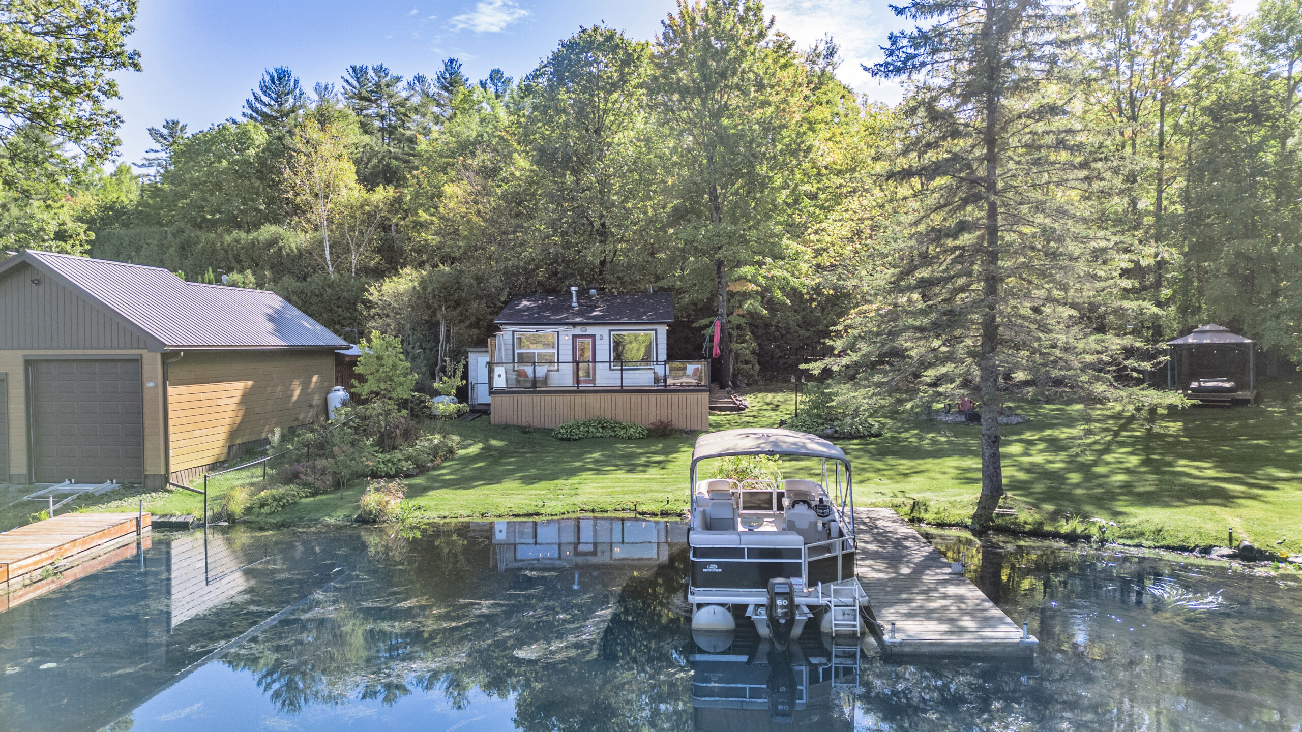 A small white cottage against a lush green property by the waterfront
