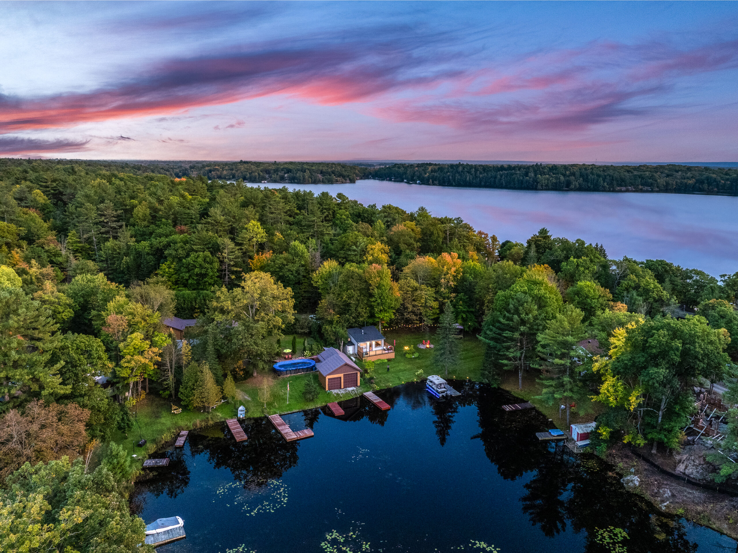 an aerial shot of a cottage and surrounding lake