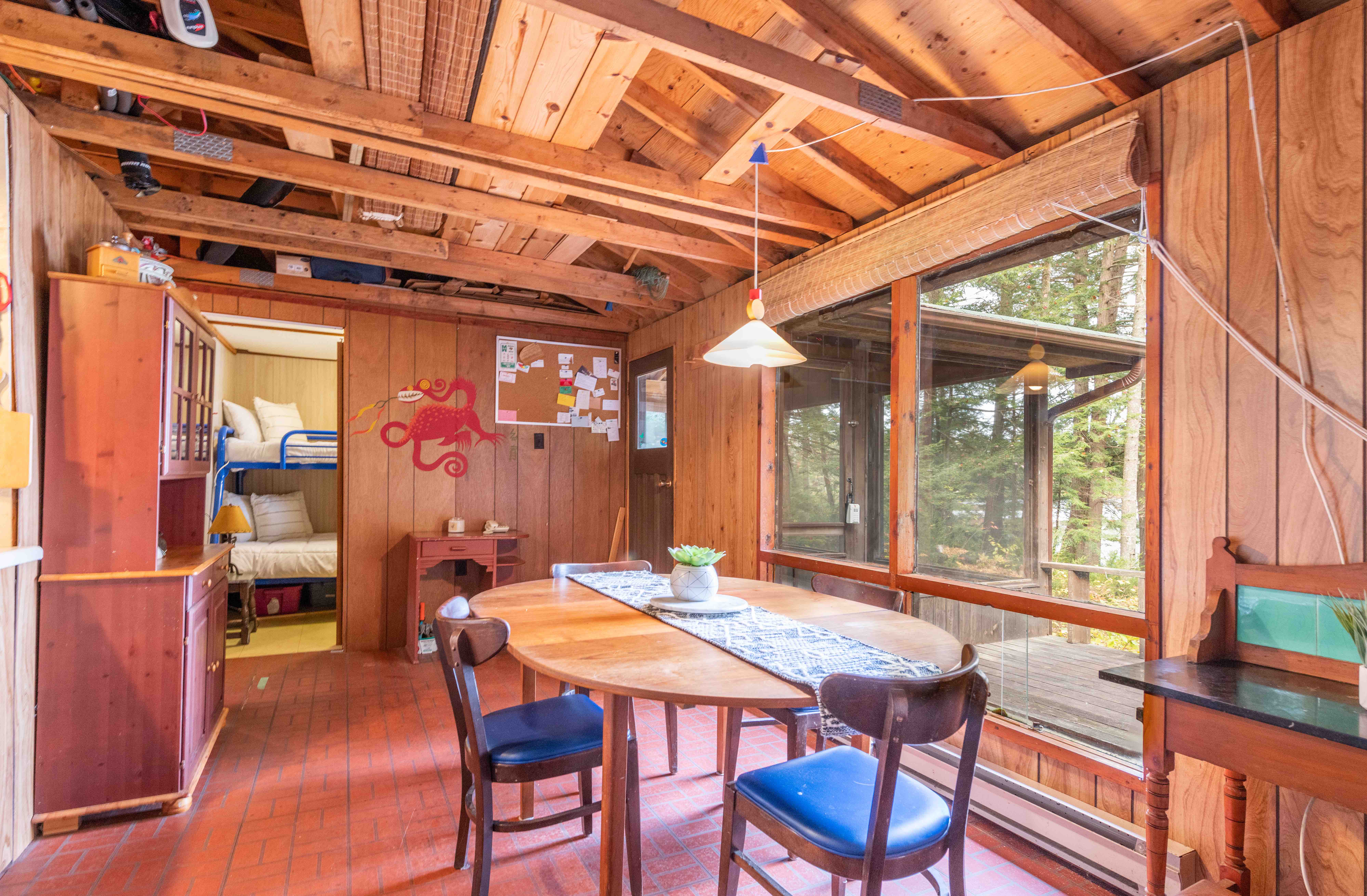 A round wood table with blue chairs around it faces a large window