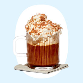 a photo of a dark drink in a clear mug with whipped cream on top