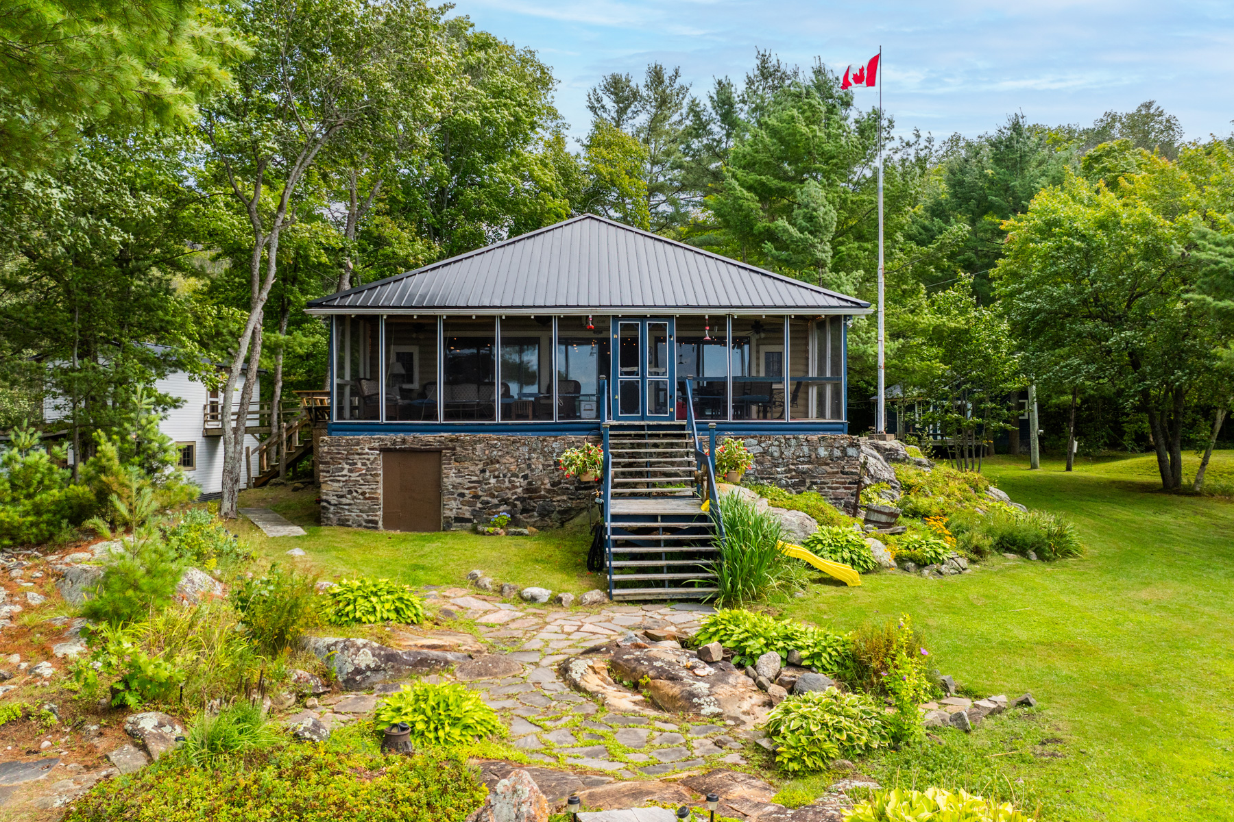 A blue cottage with huge windows and a stone foundation