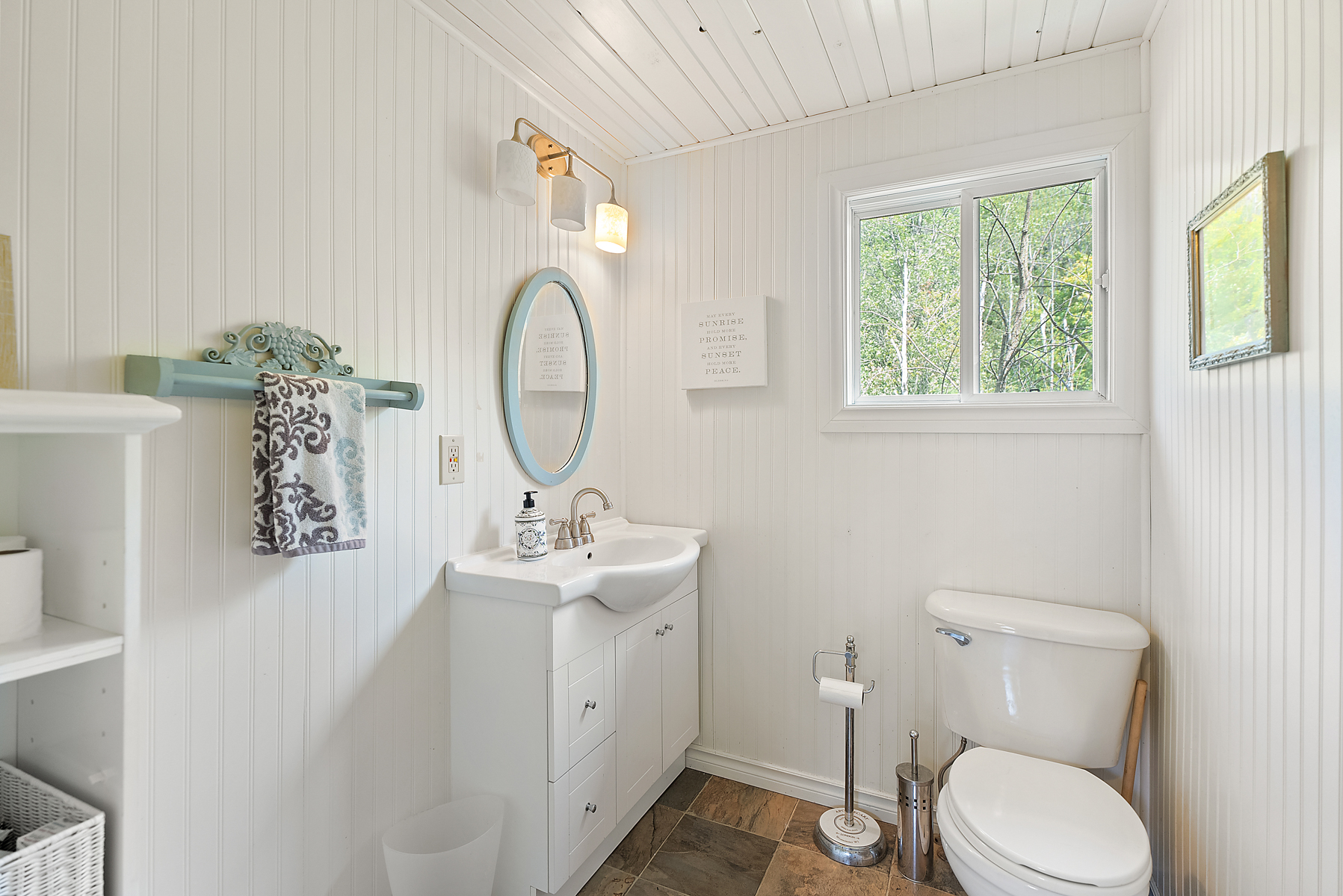 A white bathroom with a round blue mirror