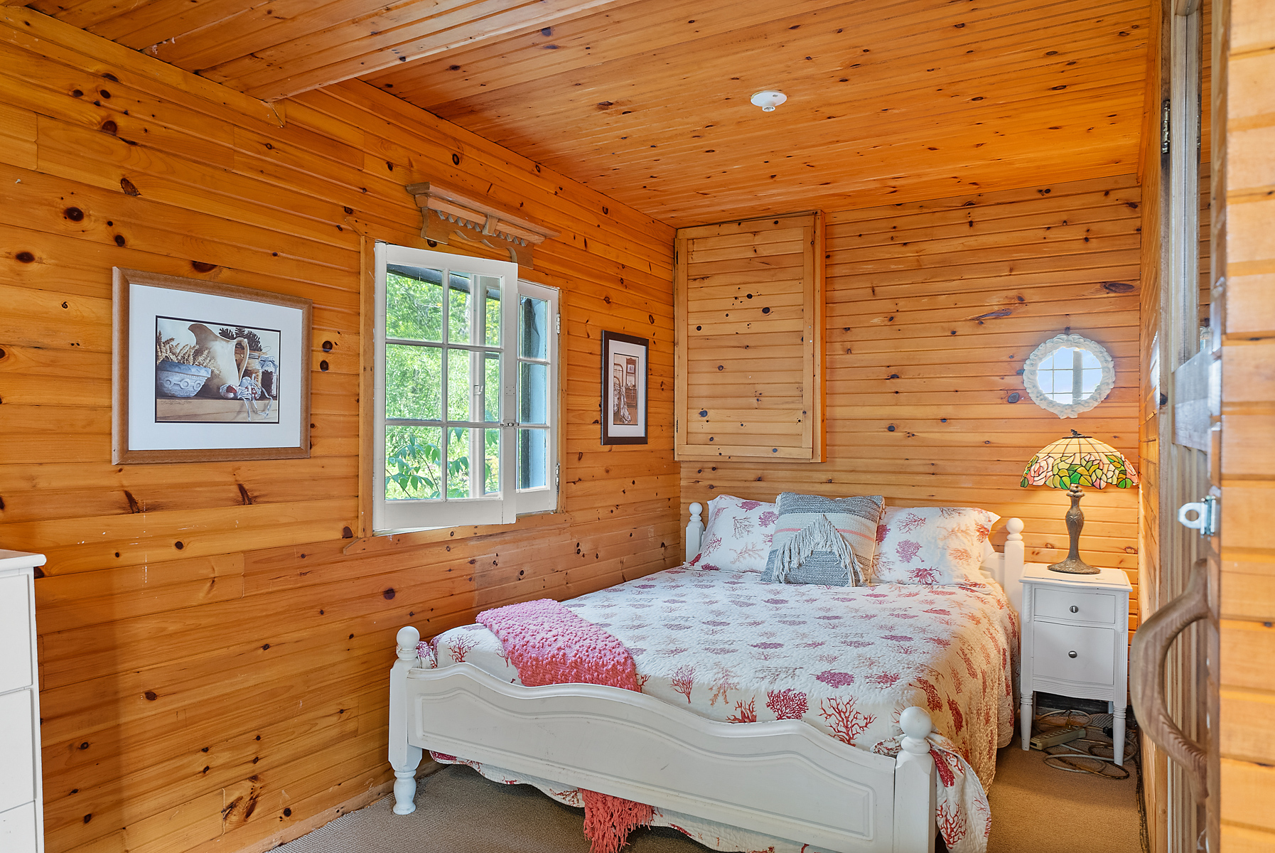 A white and pink bed in a wood-paneled room